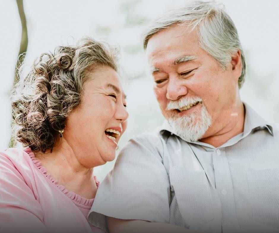 An elderly couple smiles and looks at each other