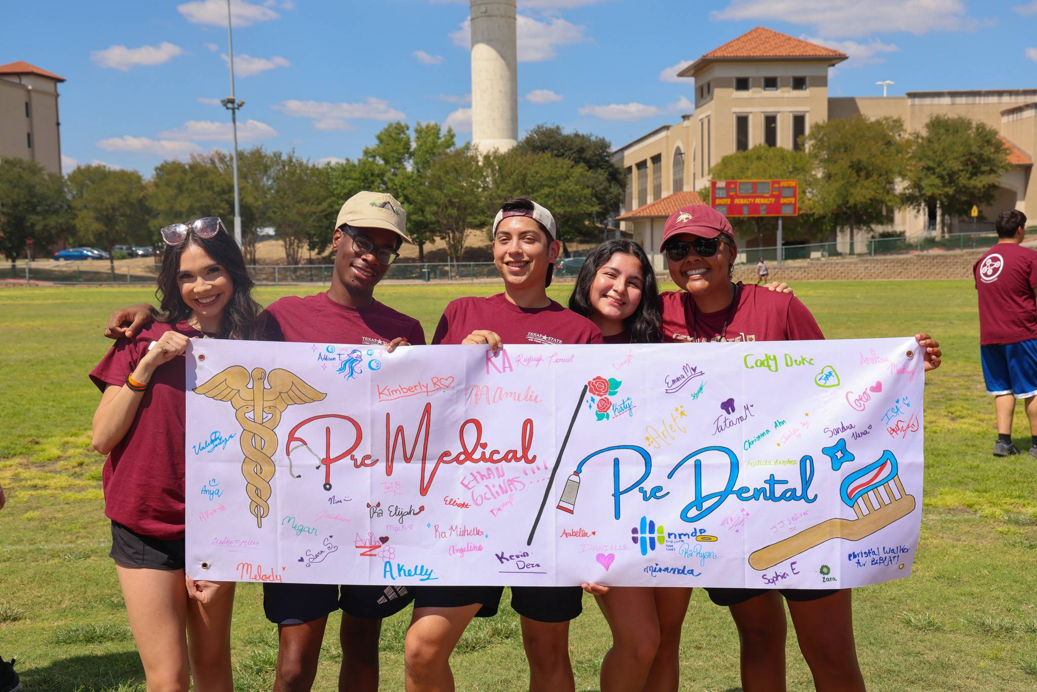 students holding a banner that says "Pre-medical, pre-dental" LLC
