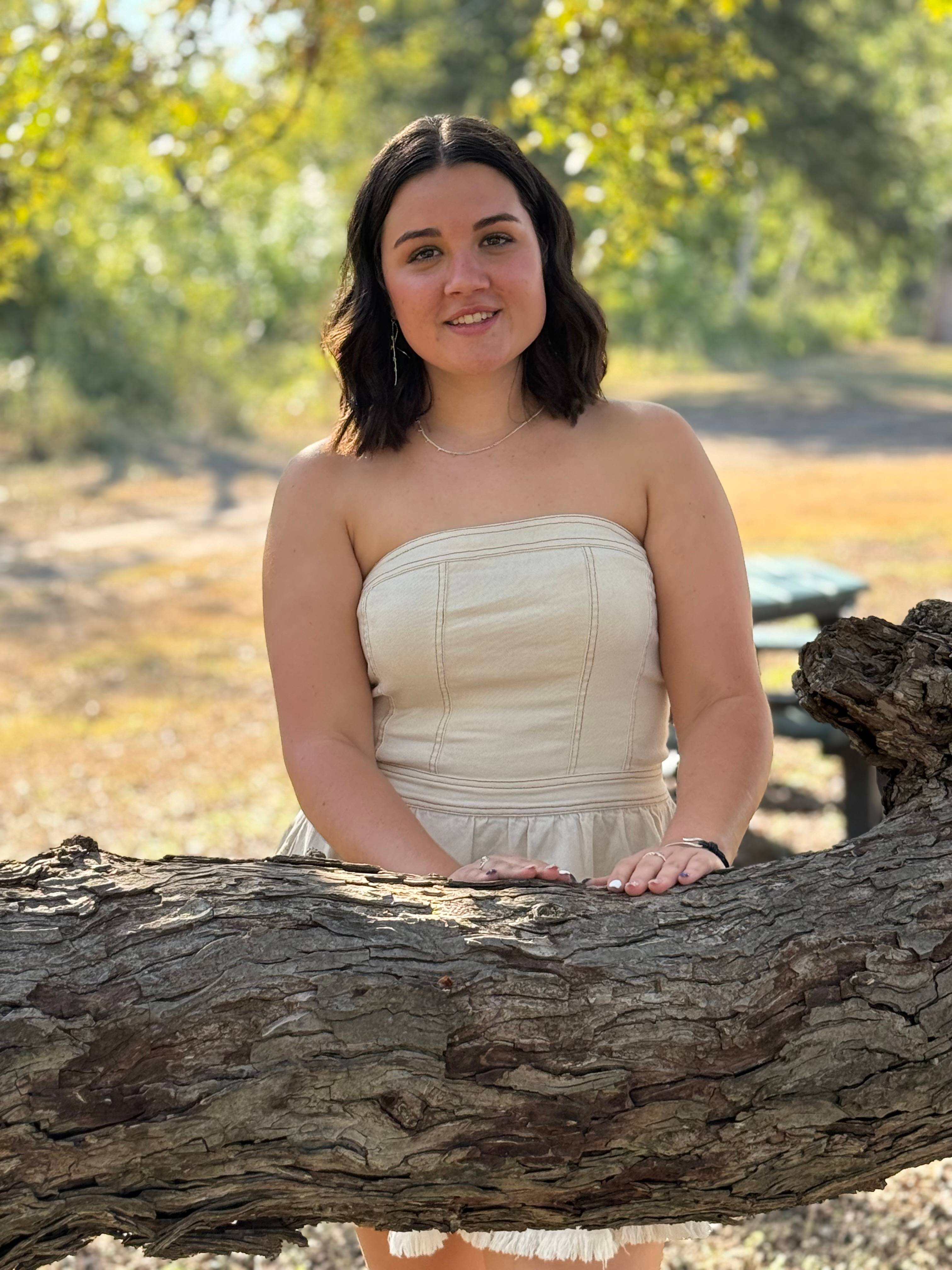 Ms. Stevens standing behind a tree log