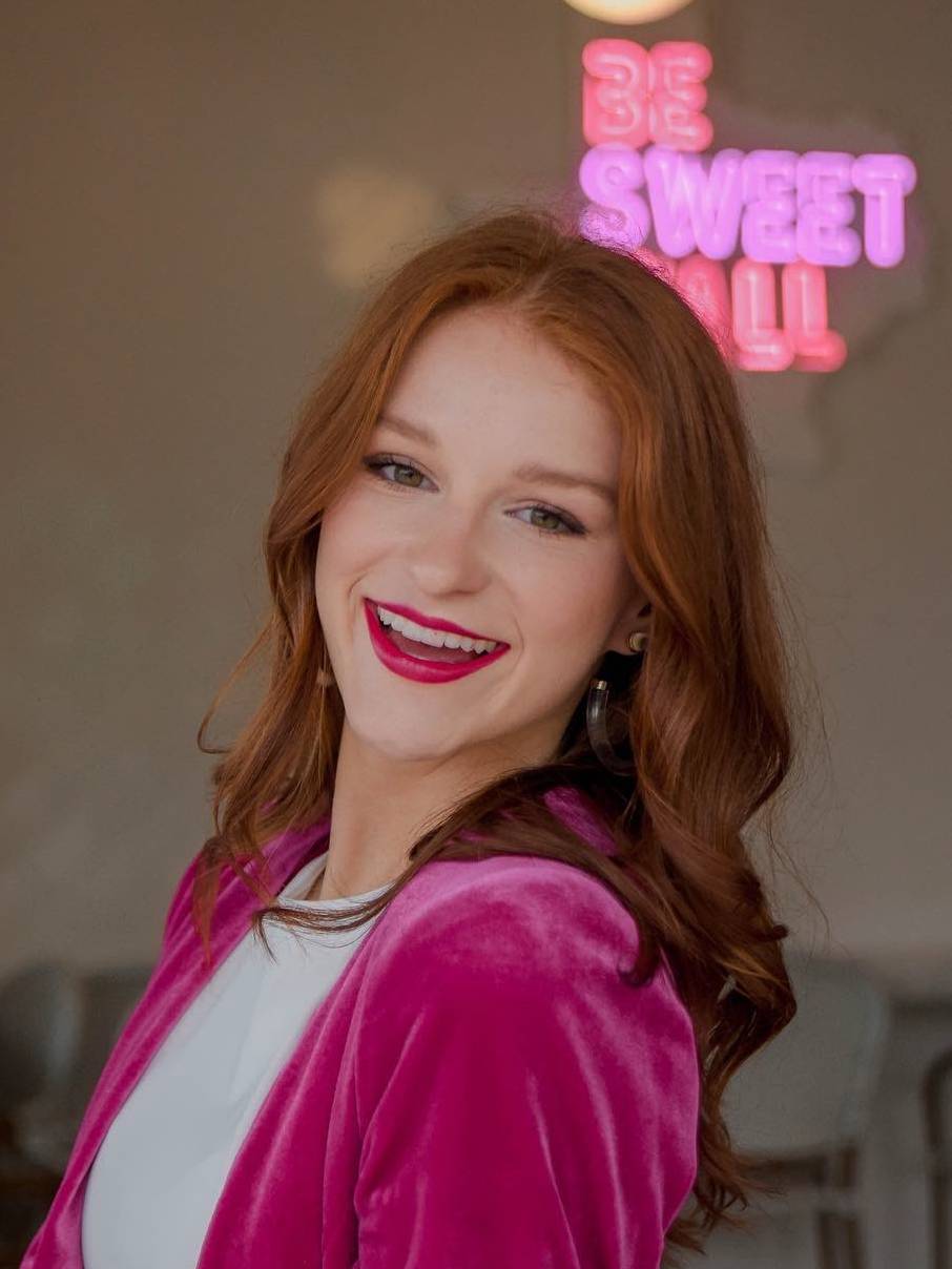 Ms. Thompson standing next to a neon sign