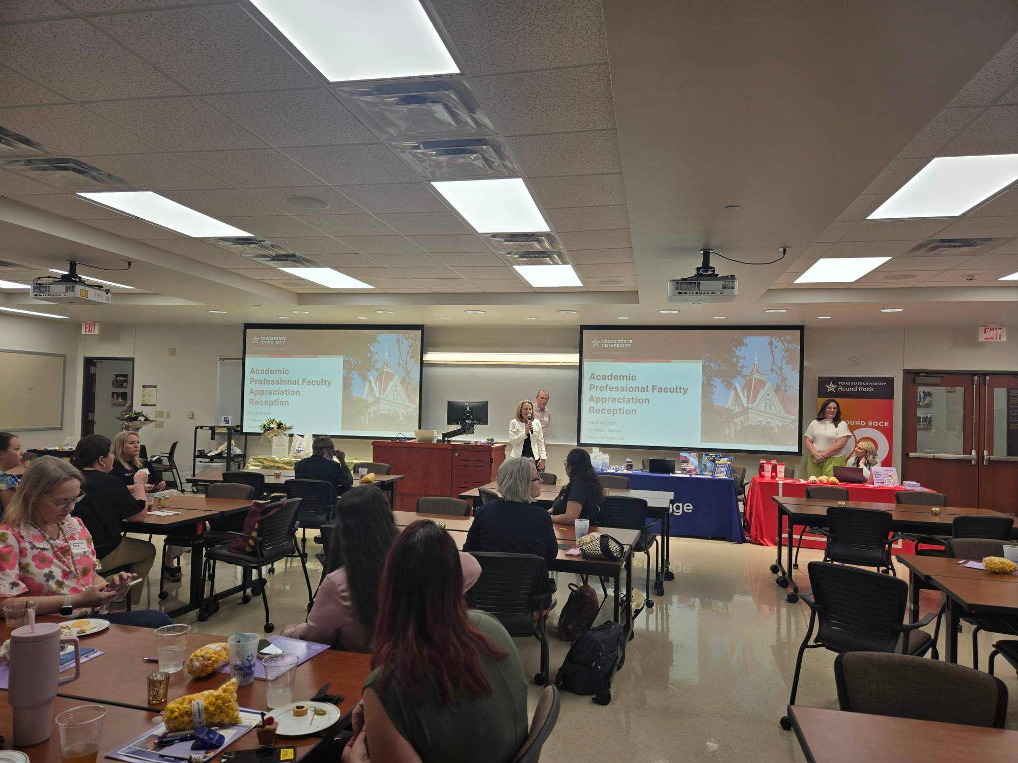 Attendees at the faculty luncheon listening to Dr. Lessiter and viewing presentation slides in a classroom setting.