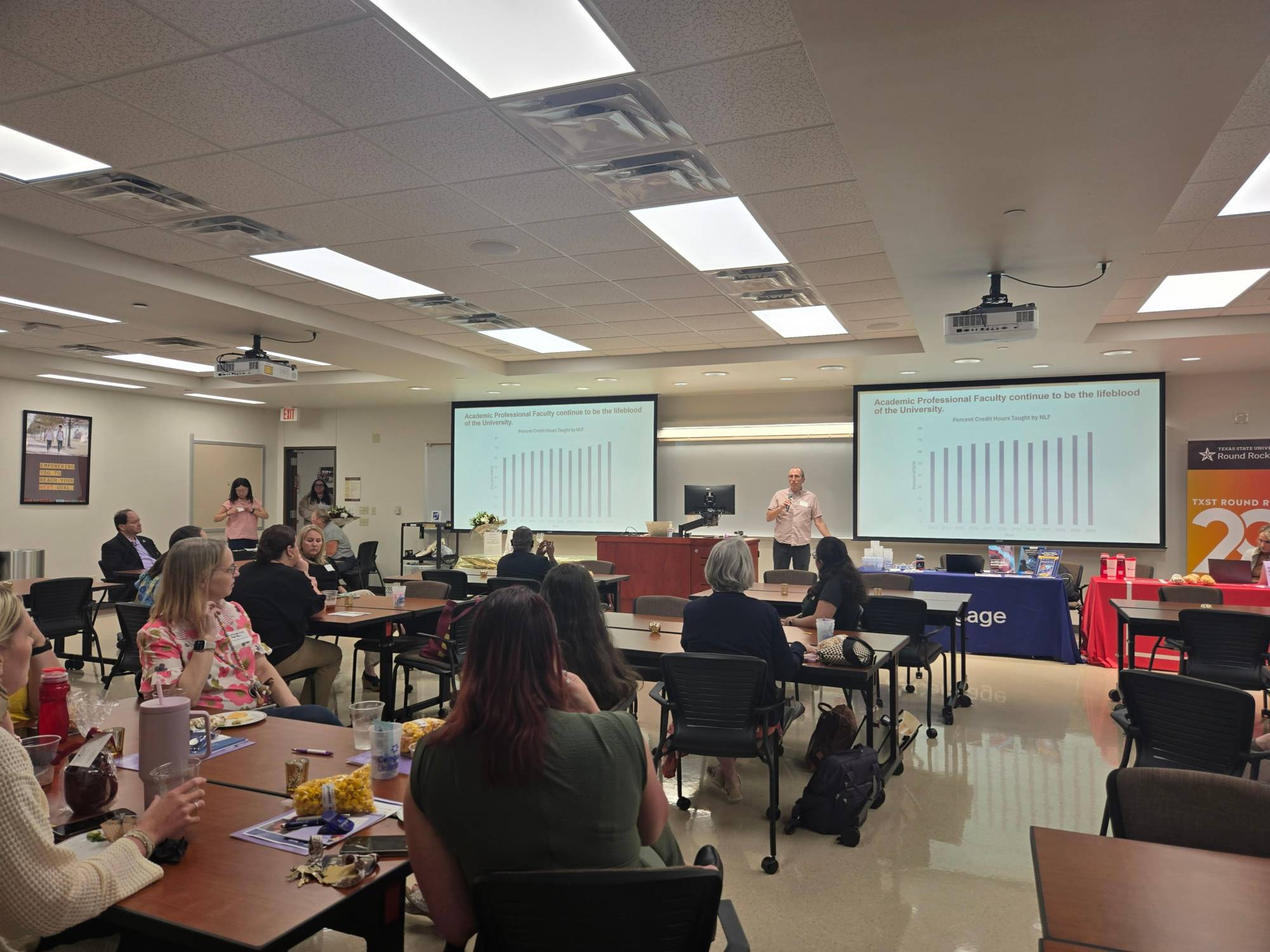 Participants at the Academic Professional Faculty Luncheon seated at tables while a presenter speaks at the front of the room.