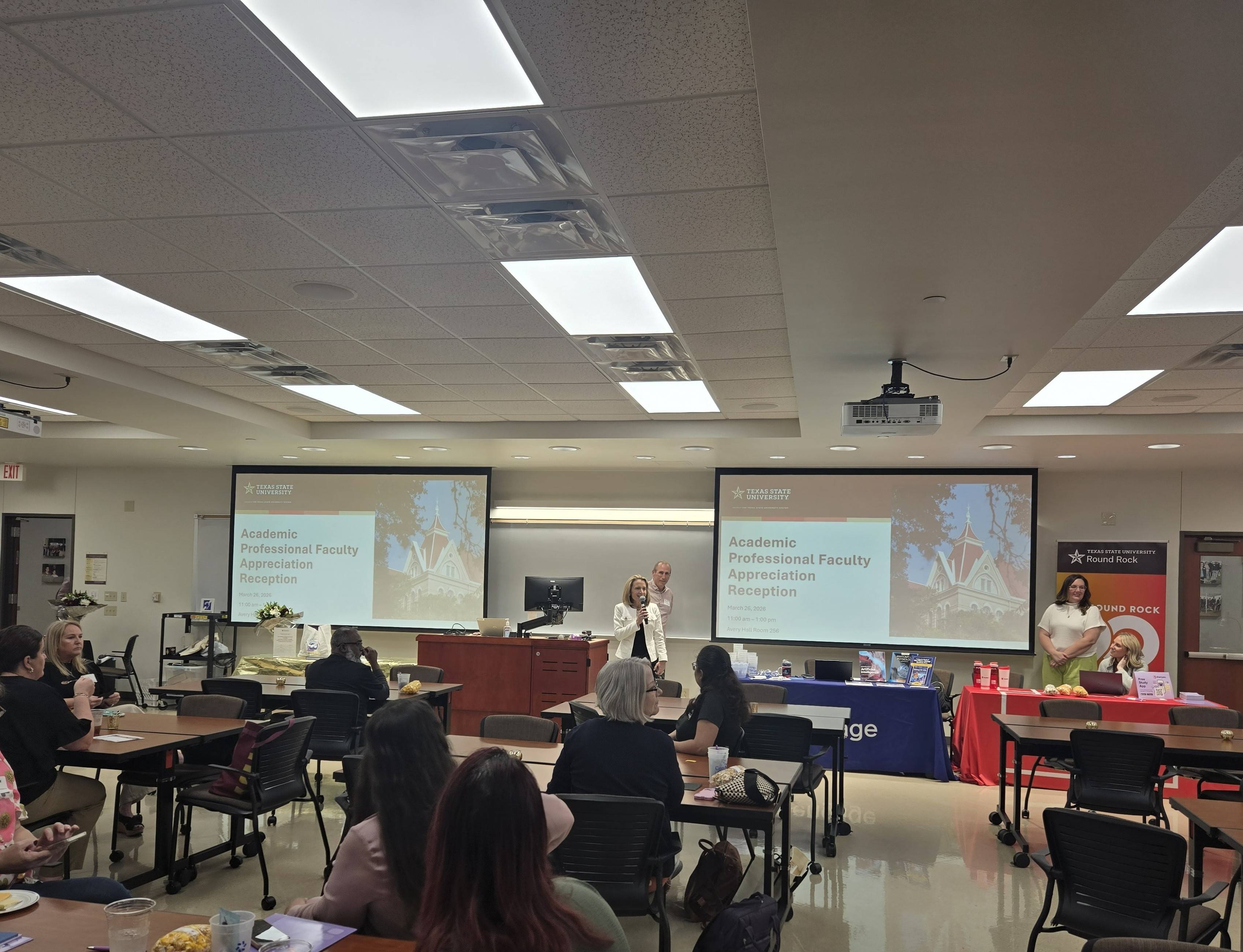 Attendees at the faculty luncheon listening to Dr. Lessiter and viewing presentation slides in a classroom setting.