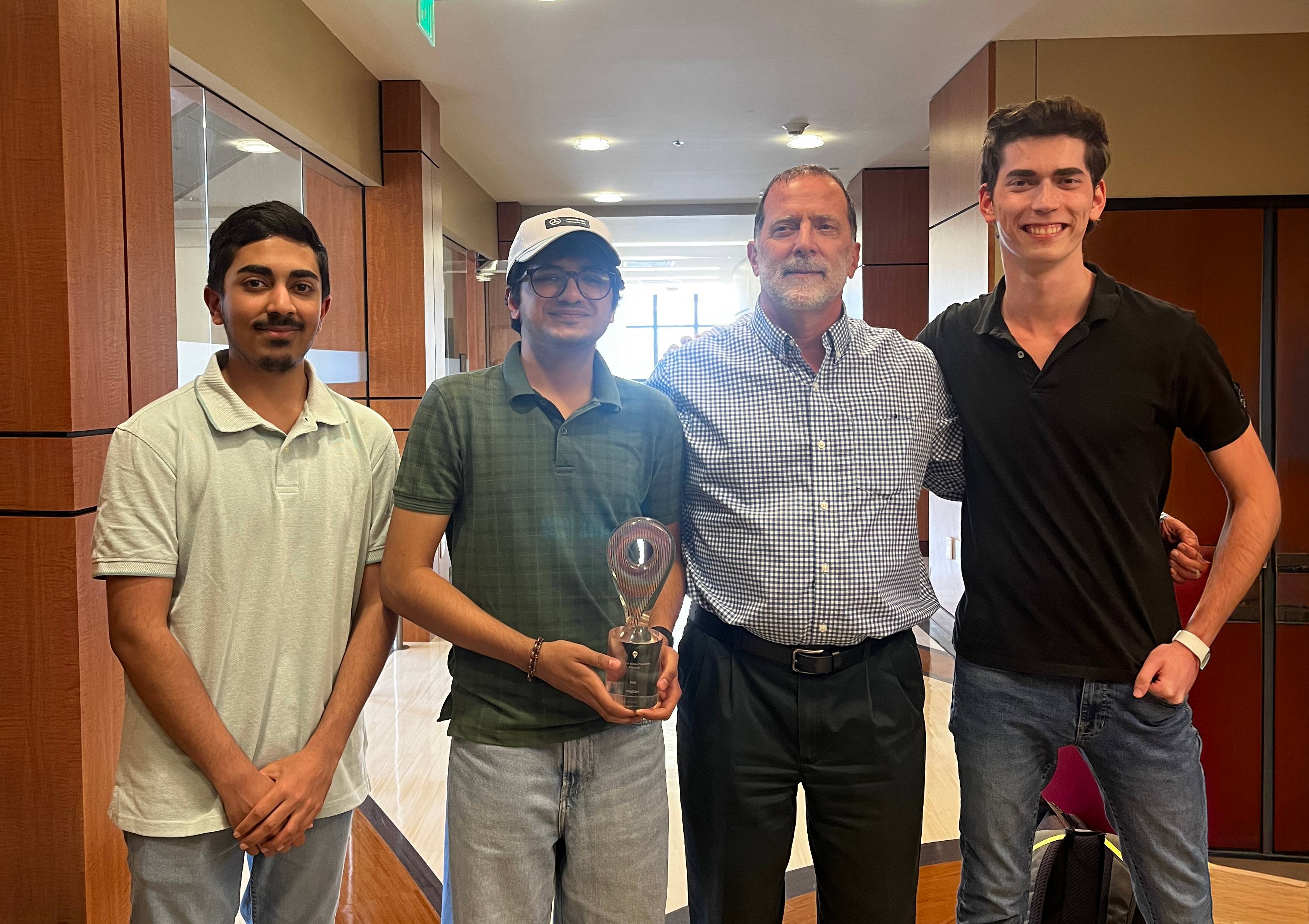 four men posing for photo while holding a trophy