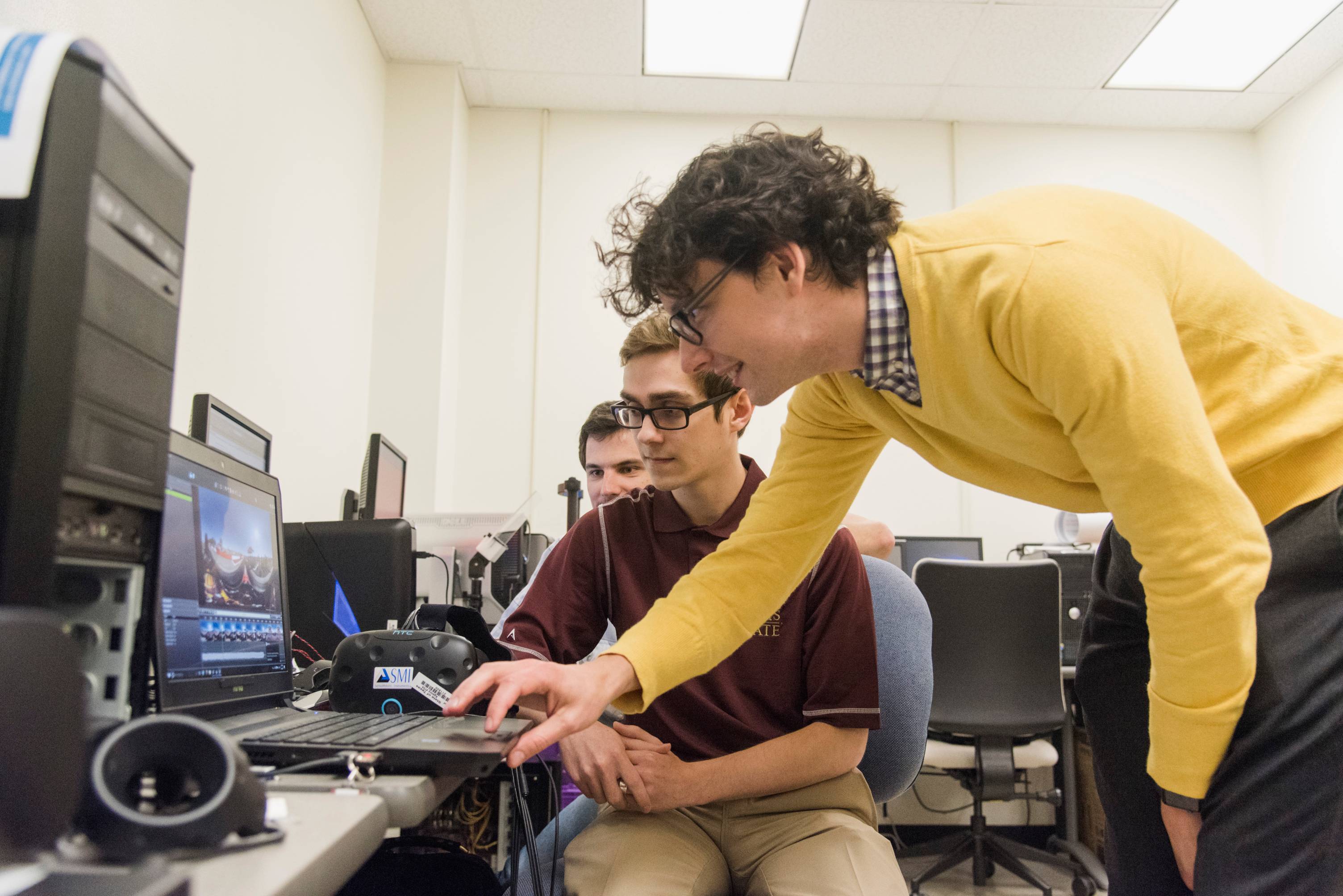 professor assisting a student at a computer