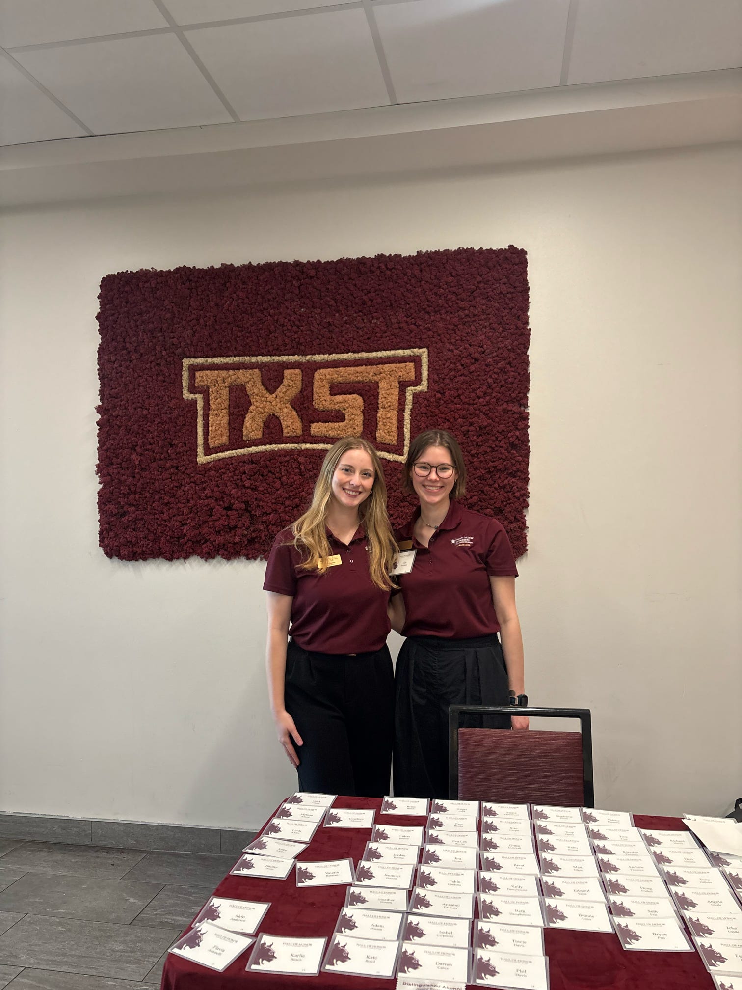 Two McCoy Ambassadors standing in front of a TXST logo
