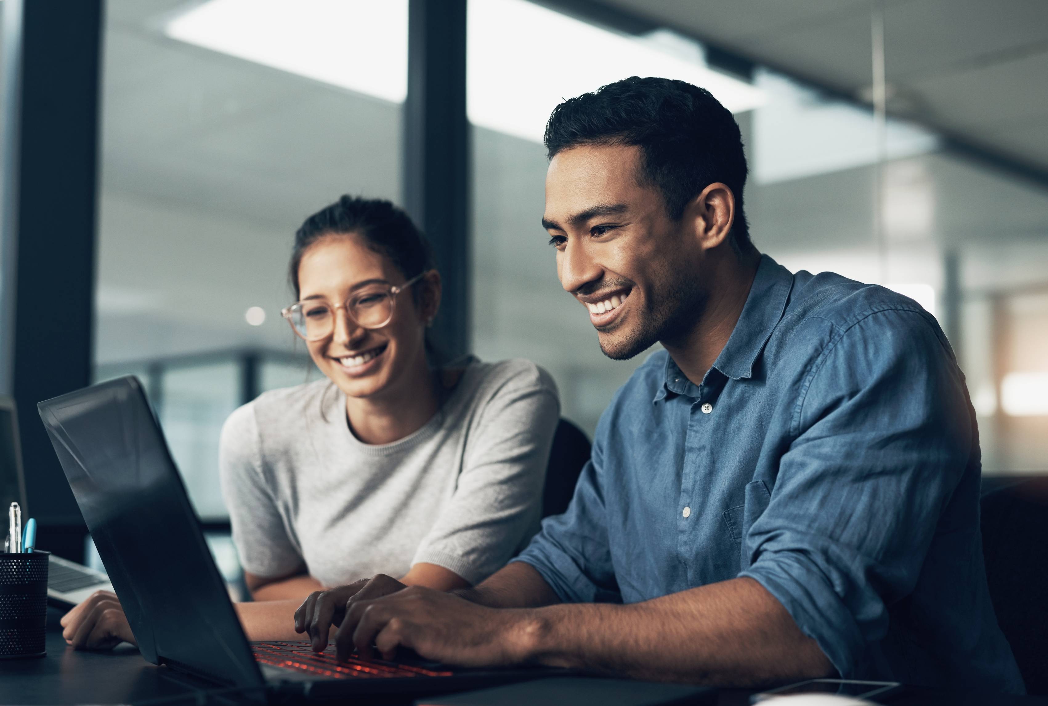 two people looking at a laptop in an office