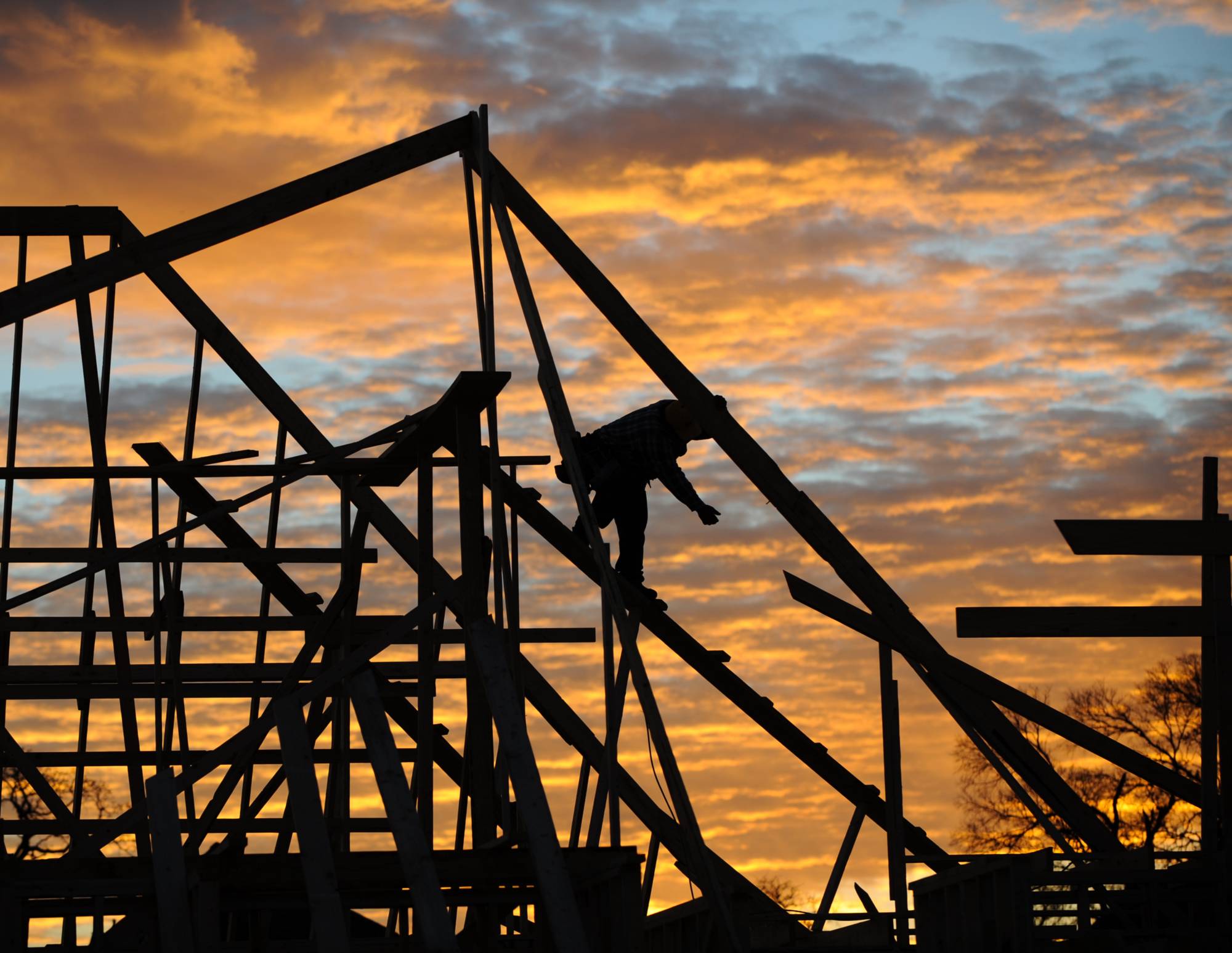 a man in silhouette on the roof of a house under construction