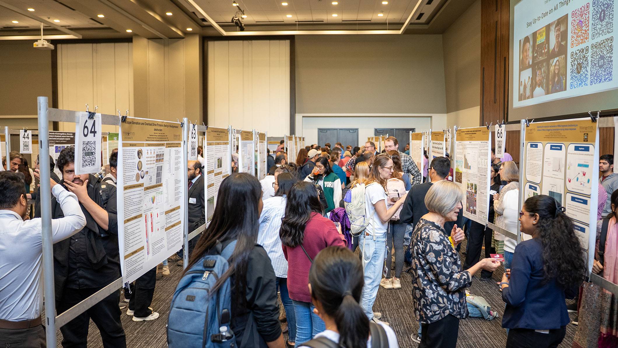 Attendees look at posters at a research conference.