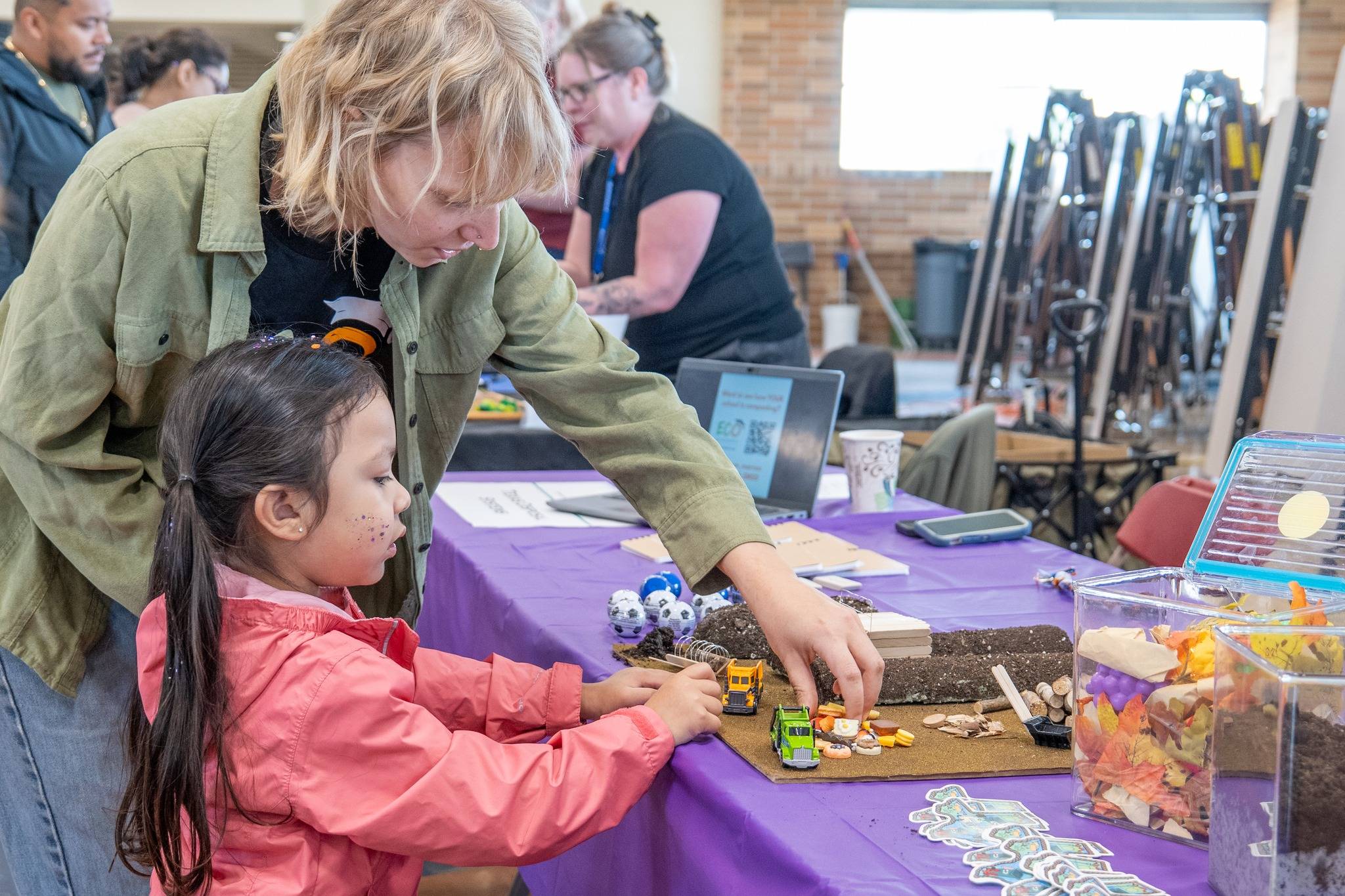 young child and an adult look at an interactive art piece on a purple tabletop