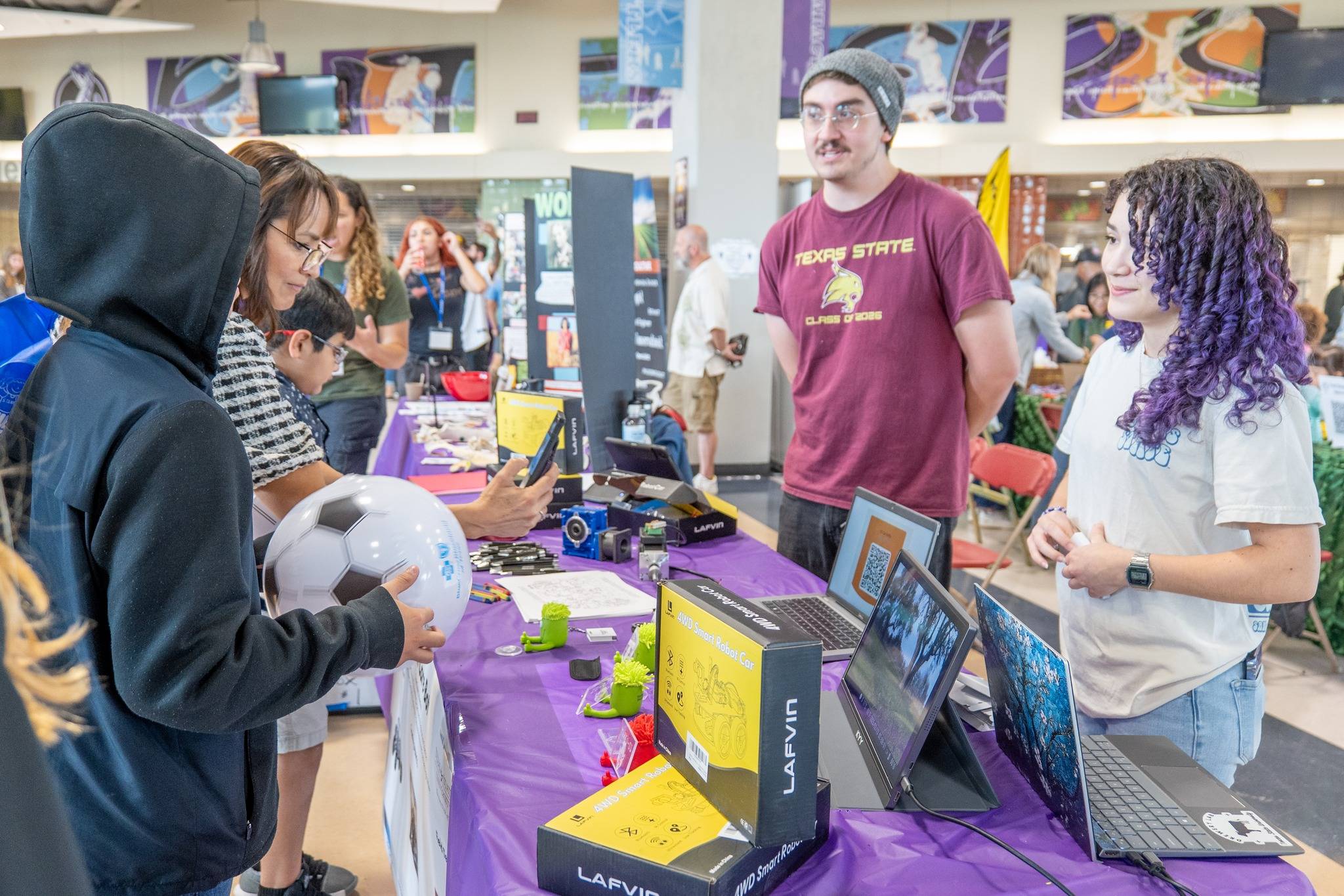 a younger student and their parent meets with two texas state students at a tabling event