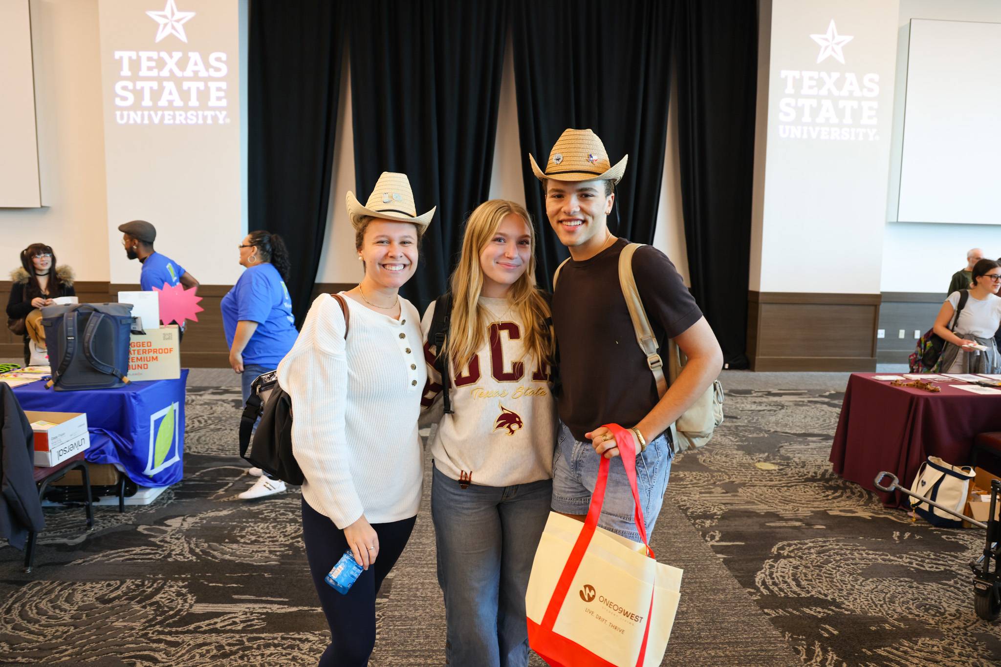 students with cowboy hats on holding swag from the spring housing event
