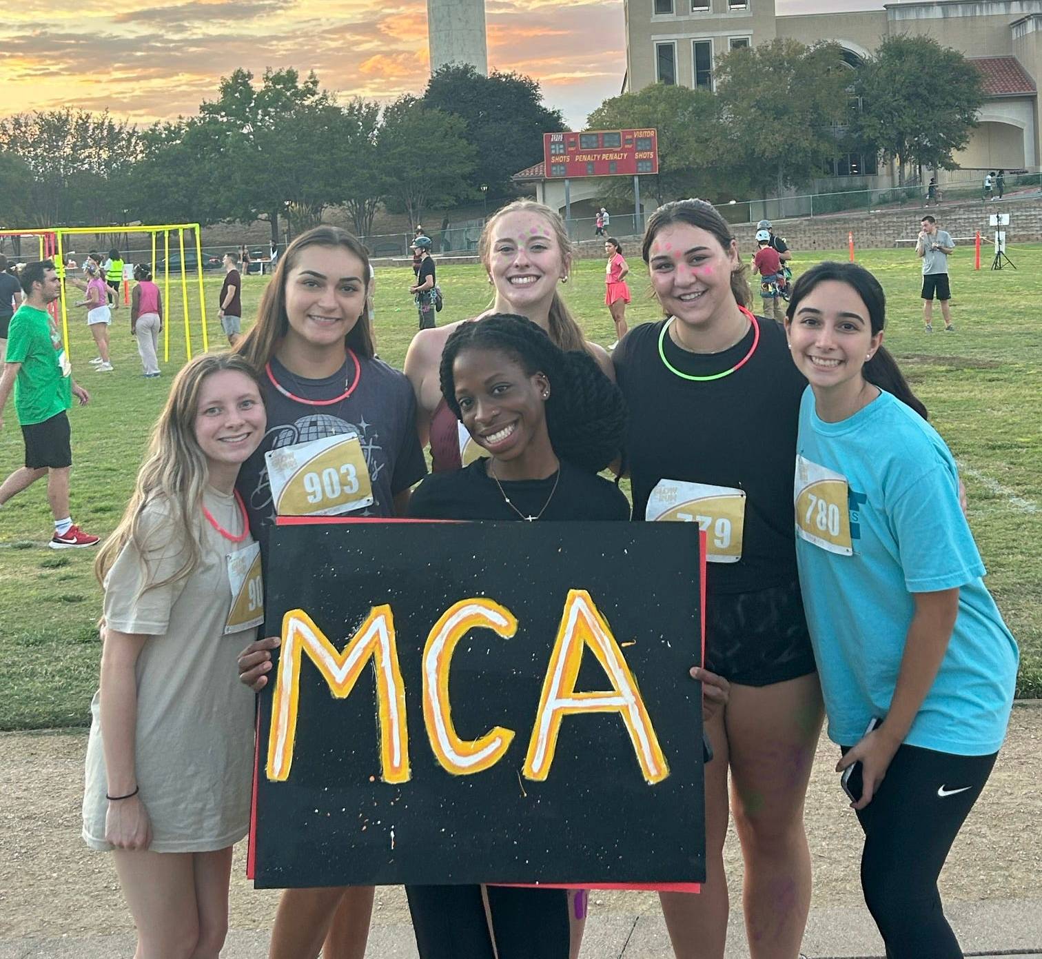 Six McCoy Ambassadors at the Boko Glow Run holding a sign that says "MCA"