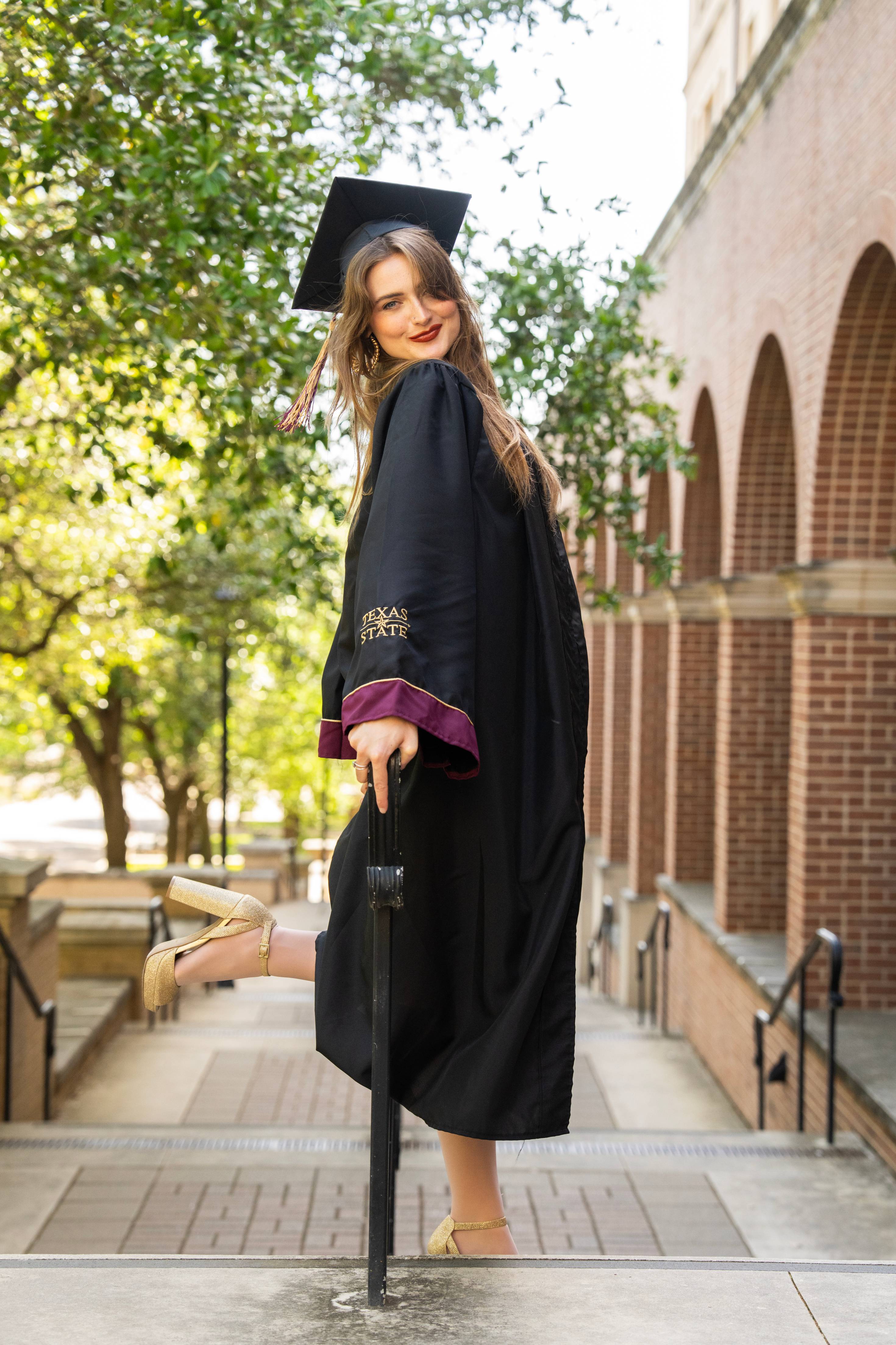 Graduate poses in front of the brick arched walkway at Trauth Huffman.