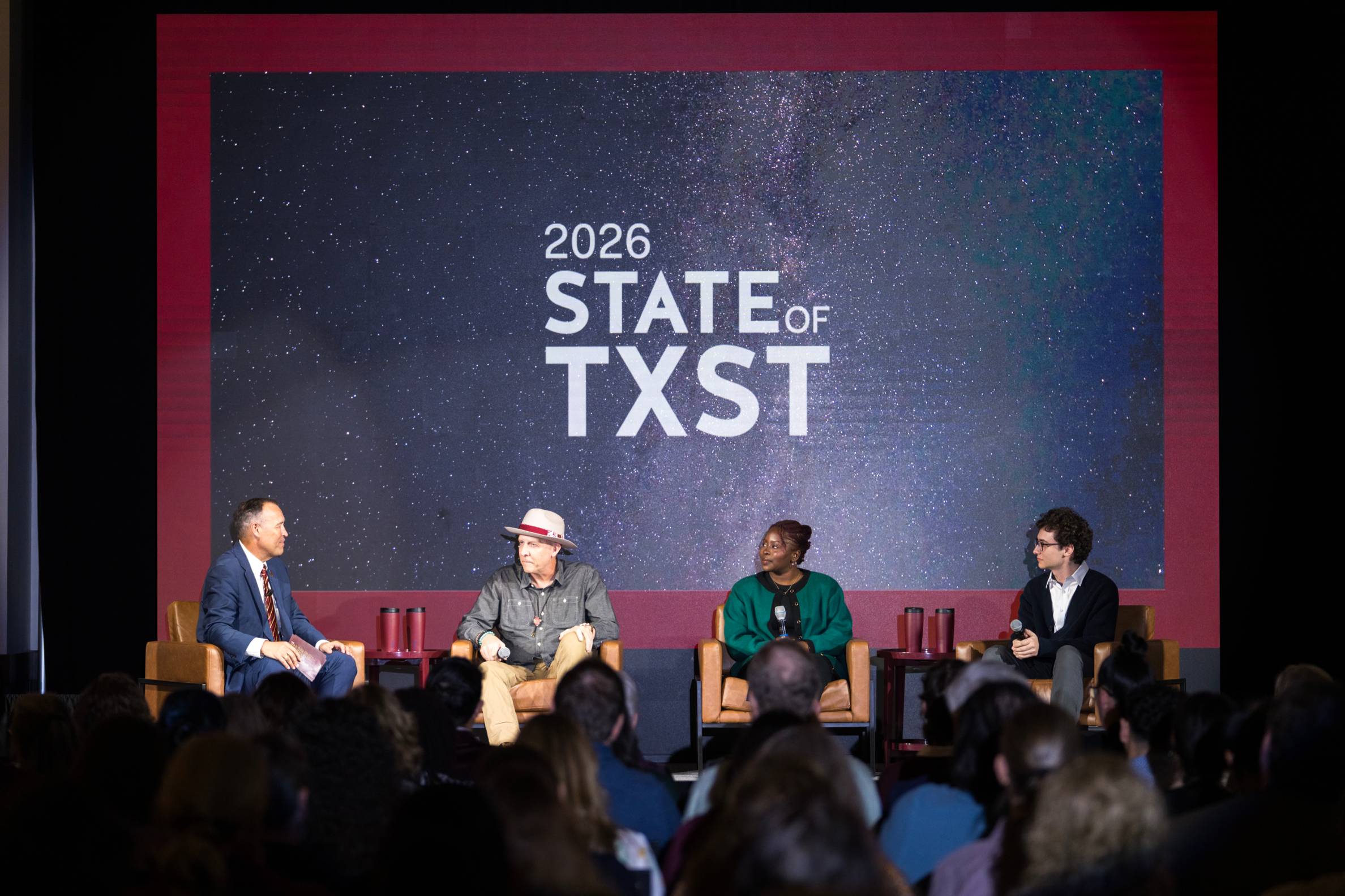 four people sit on a stage while holding microphones. "2026 State of TXST" is displayed behind them. 