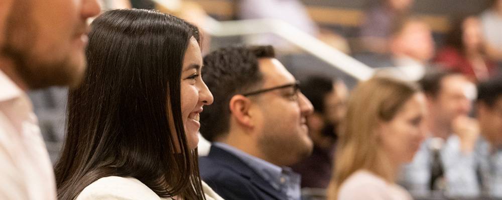 Students in business attire smiling in auditorium seats