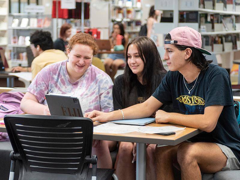 students sitting at a table with laptop
