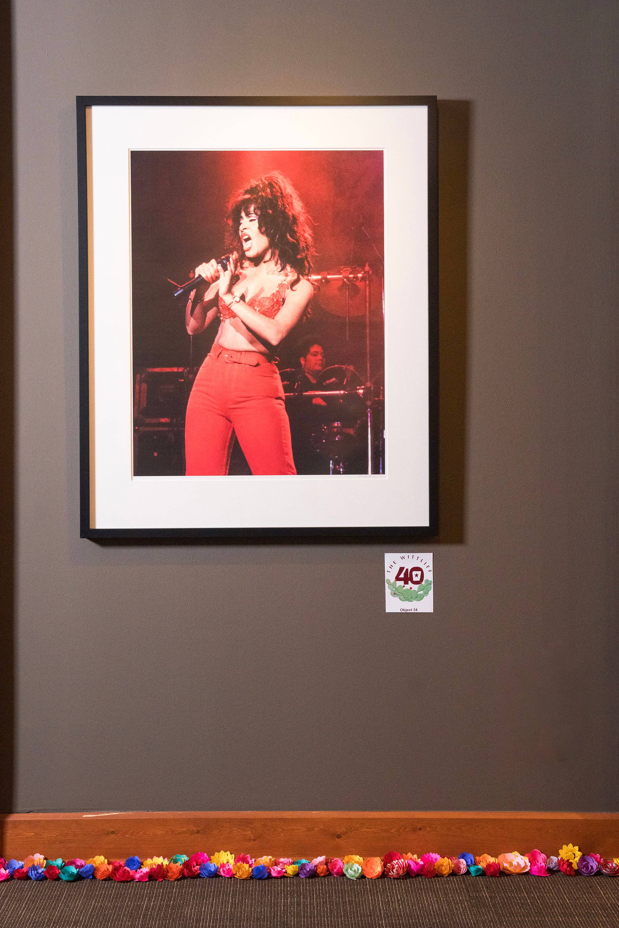 Portrait of Selena hanging on the wall with the bottom edge of the floor adorned with colorful paper flowers. 