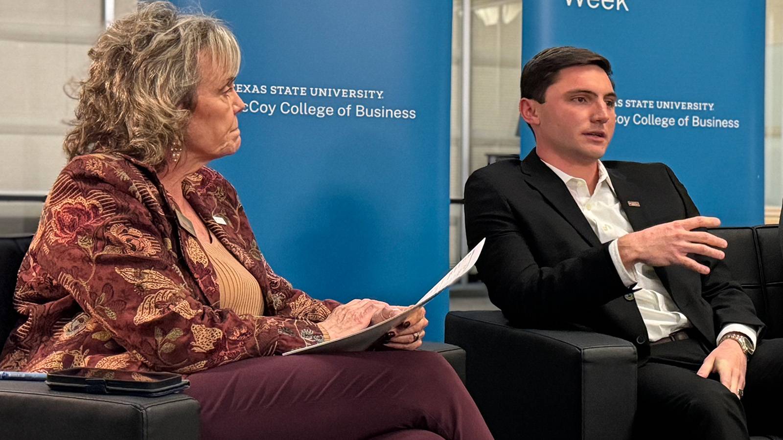 a woman looks at a student as he speaks during a panel session