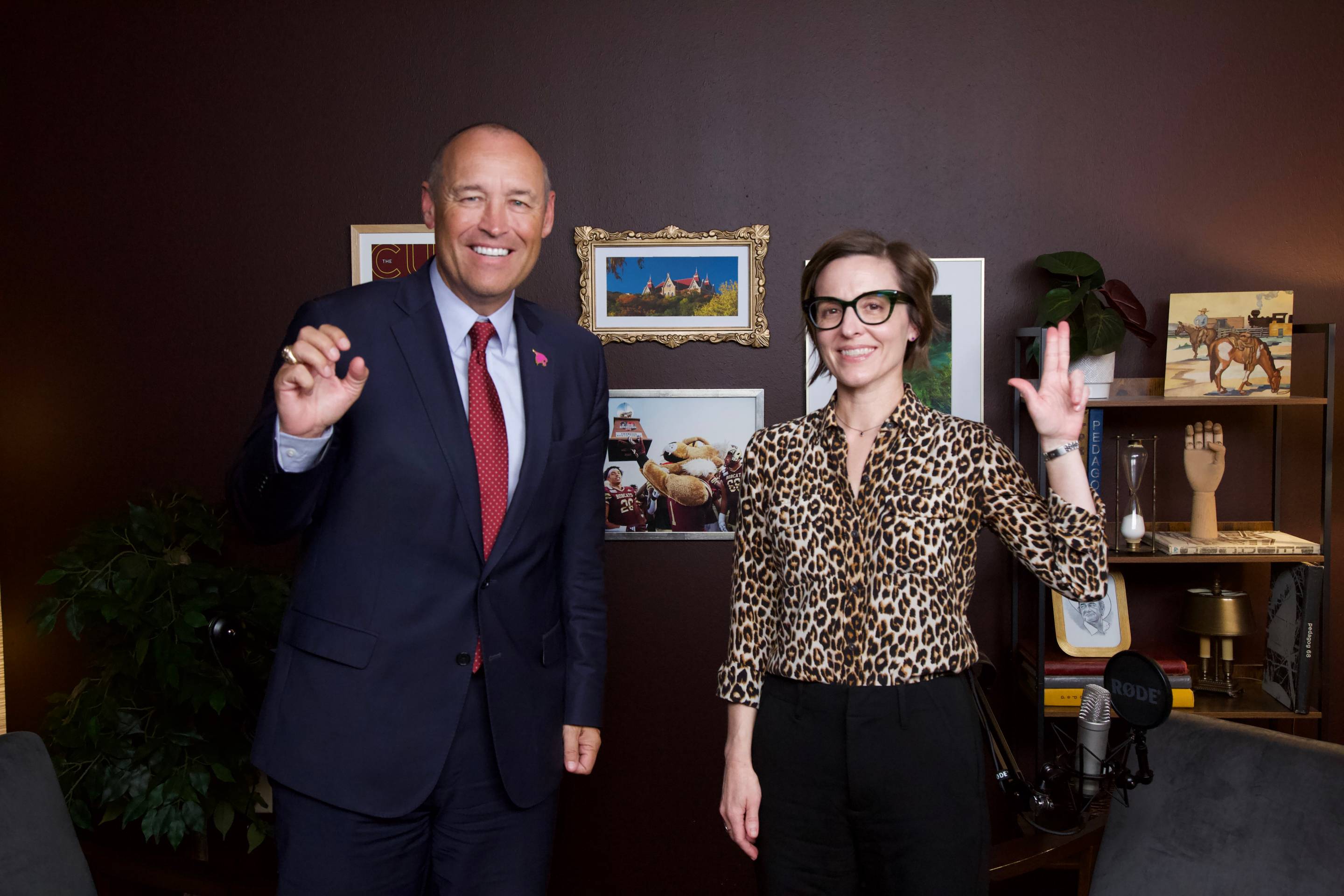 president kelly damphousse and dr kate spradley stand for a photo with txst hand signs up