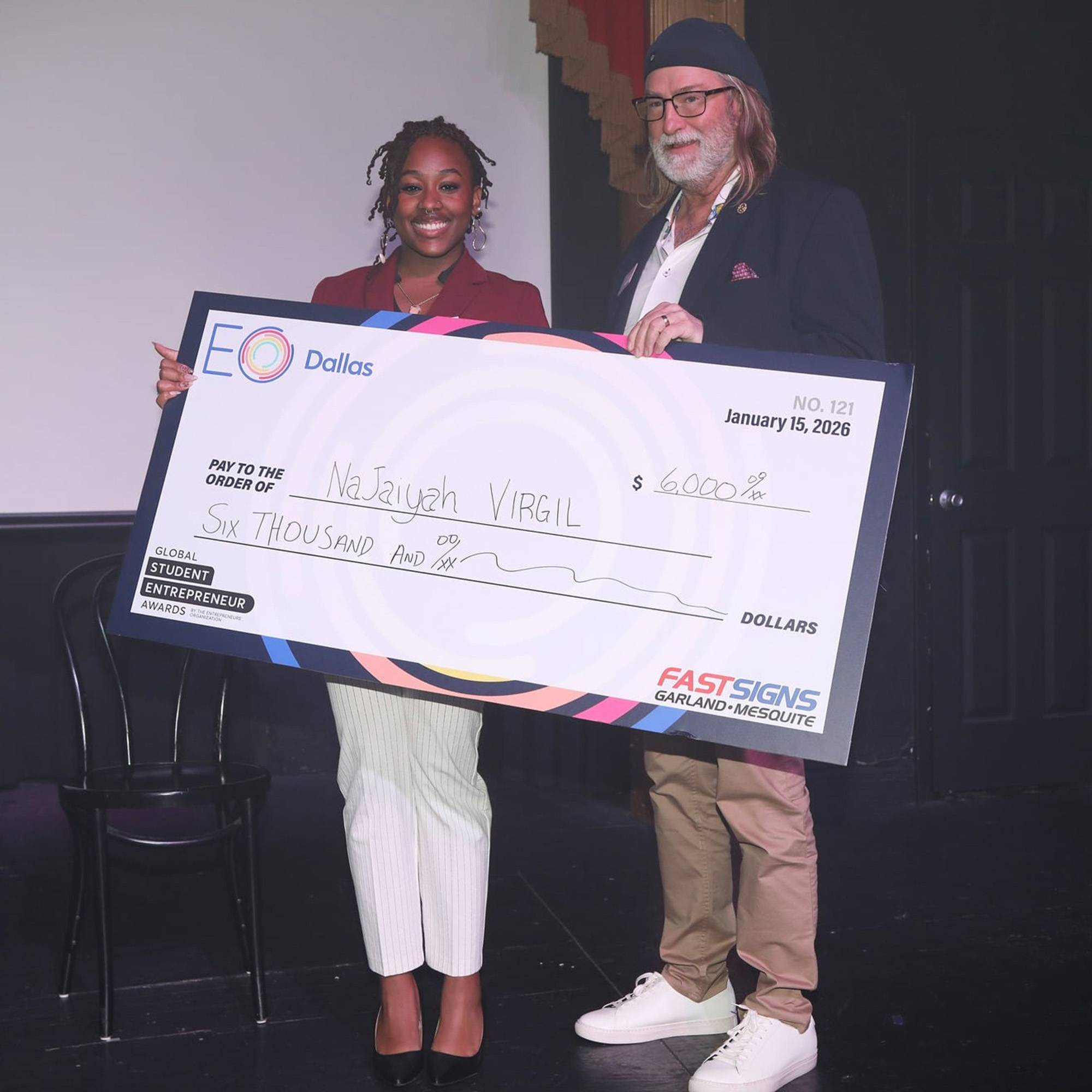 student and older man holding a life size check at a competition