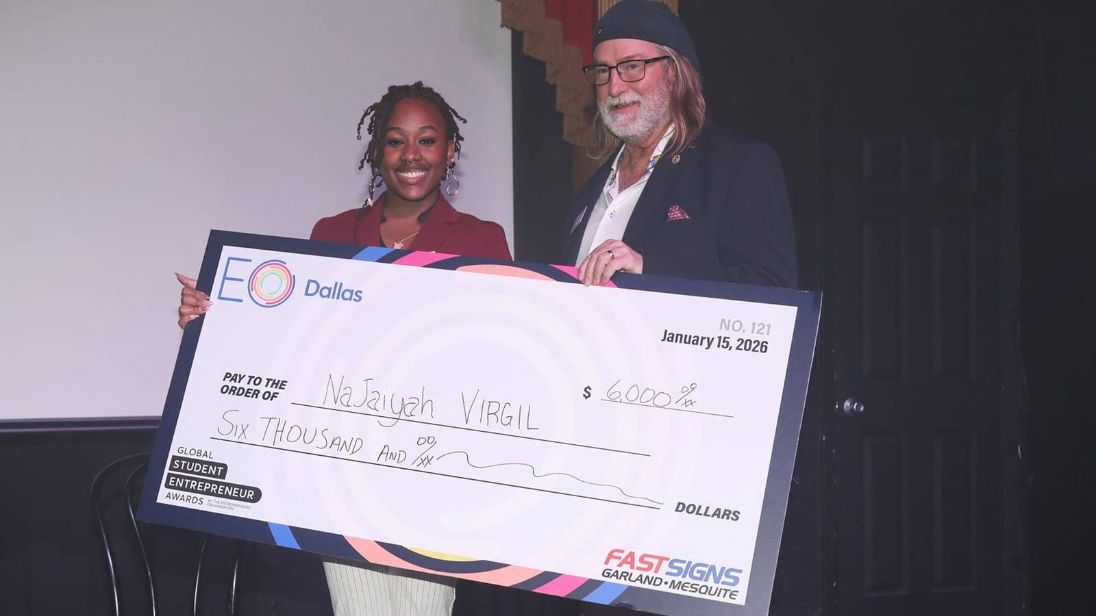 student and older man holding a life size check at a competition