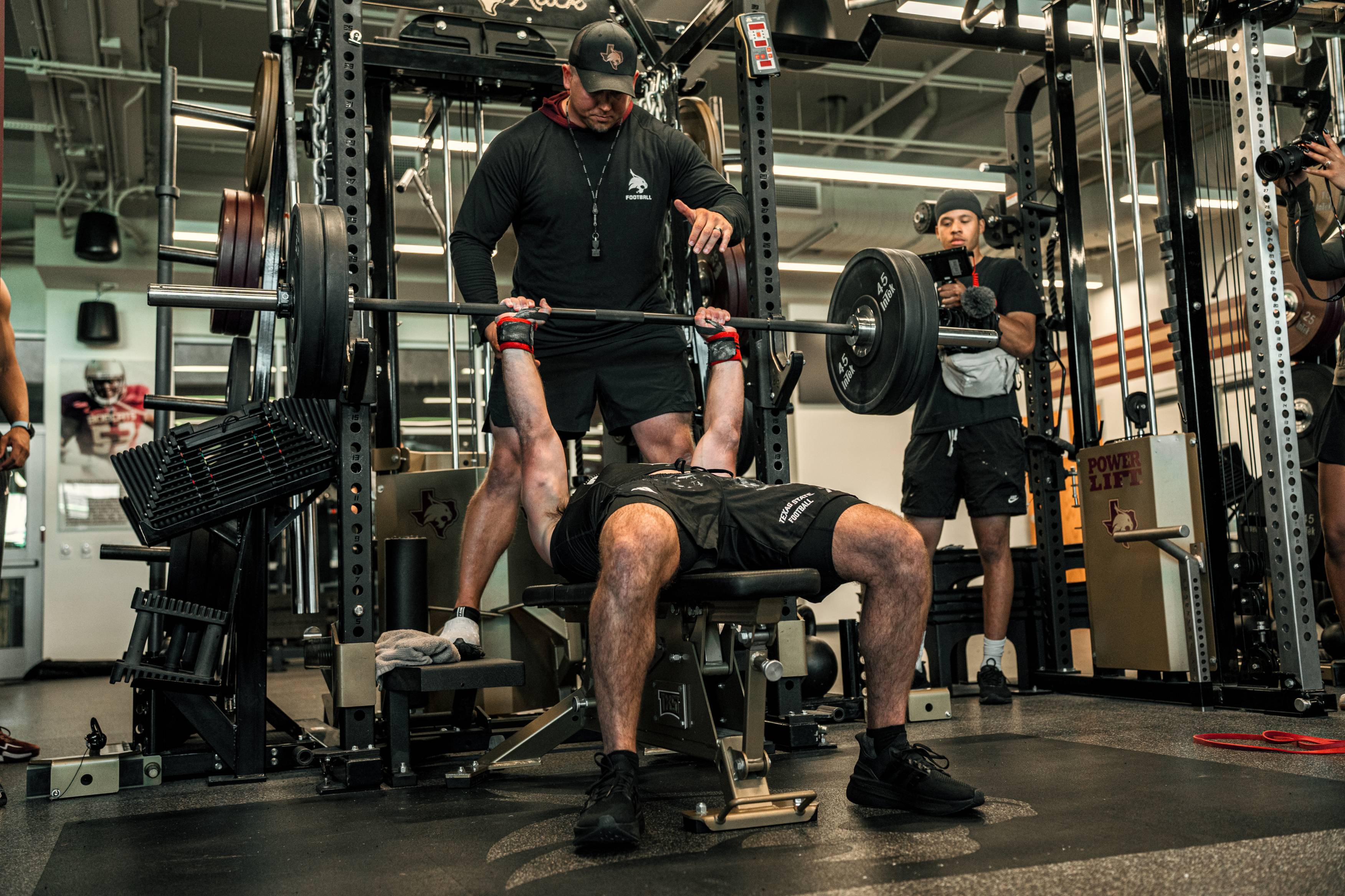 man doing benchpress exercises while another man stands to spot him