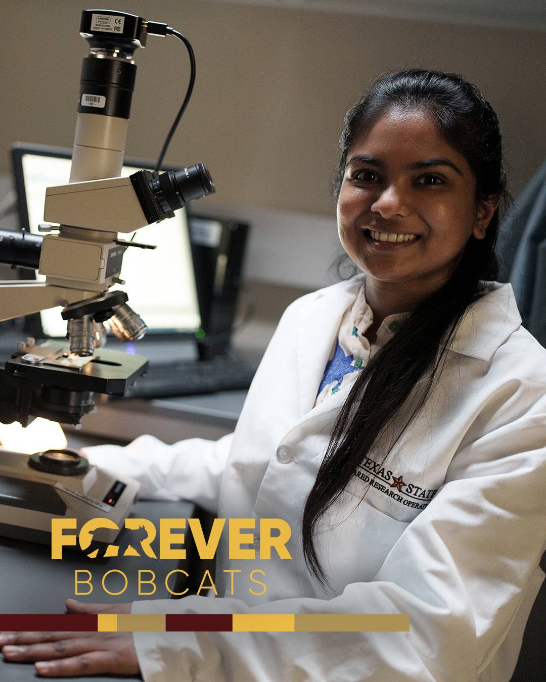 Student wearing a lab coat with a Texas State logo and using a microscope with a Forever Bobcat logo overlayed on top of the image