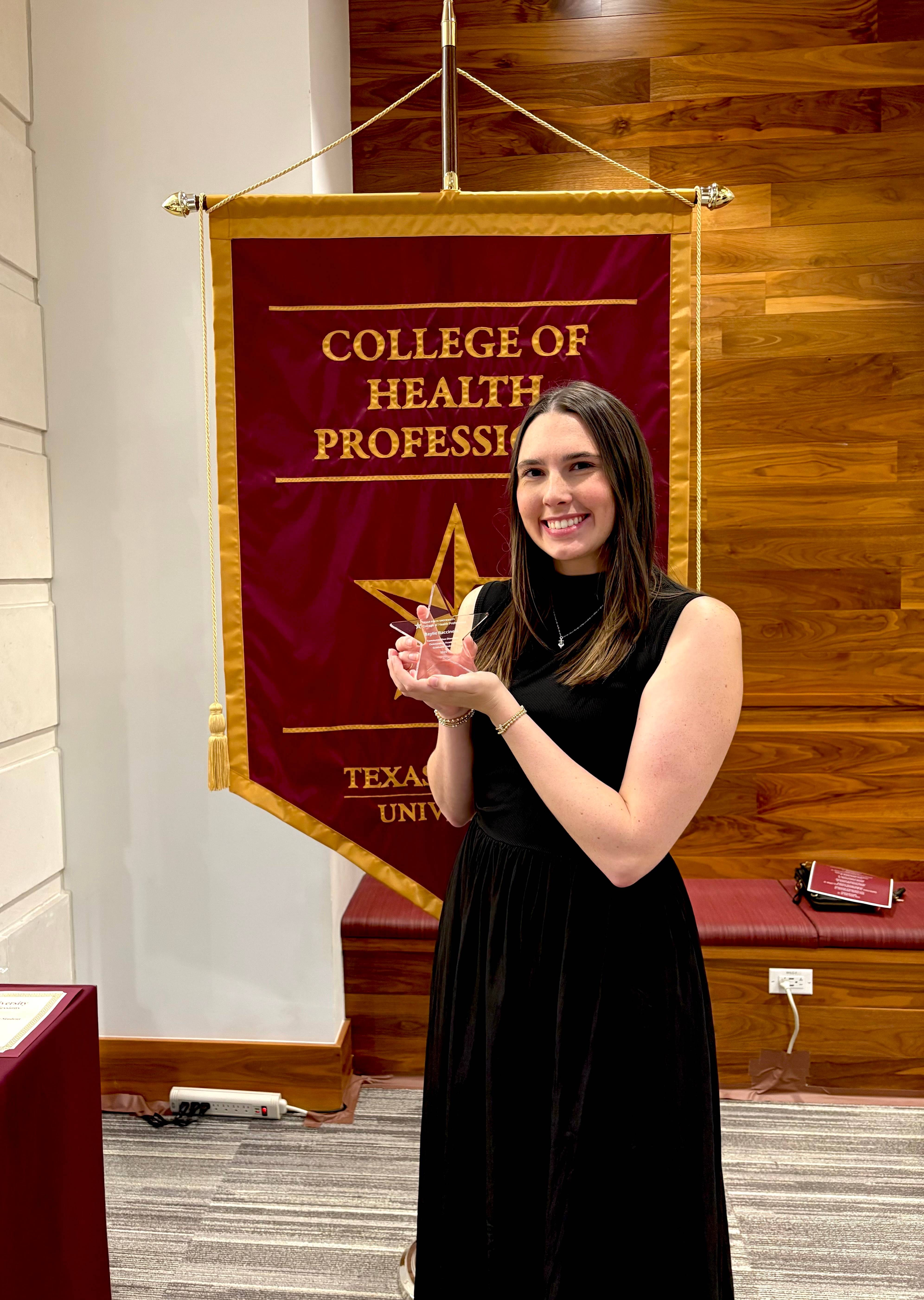 Ms. Baccinelli standing next to the College of Health Professions  banner during the event.