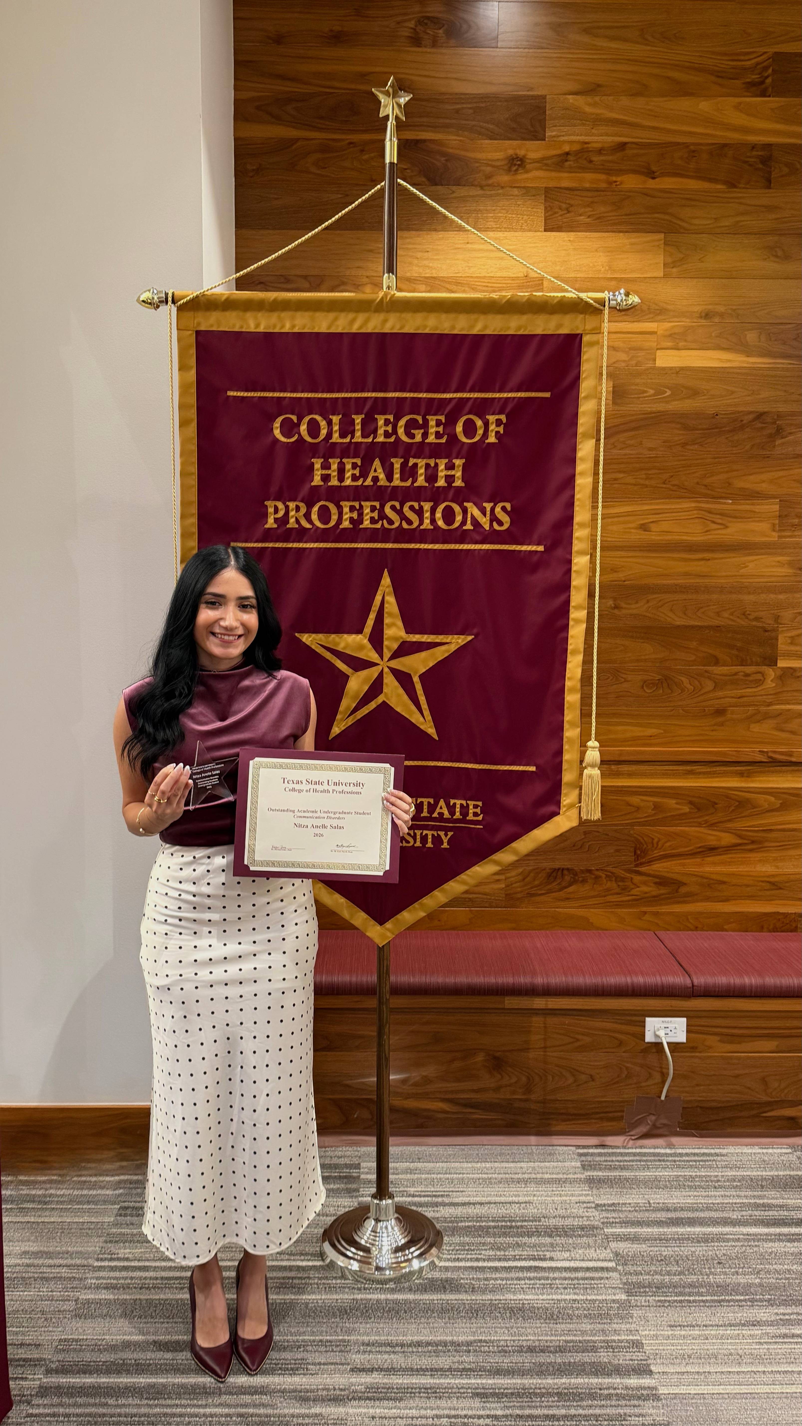 Ms. Salas standing next to the College of Health Professions banner during the event.
