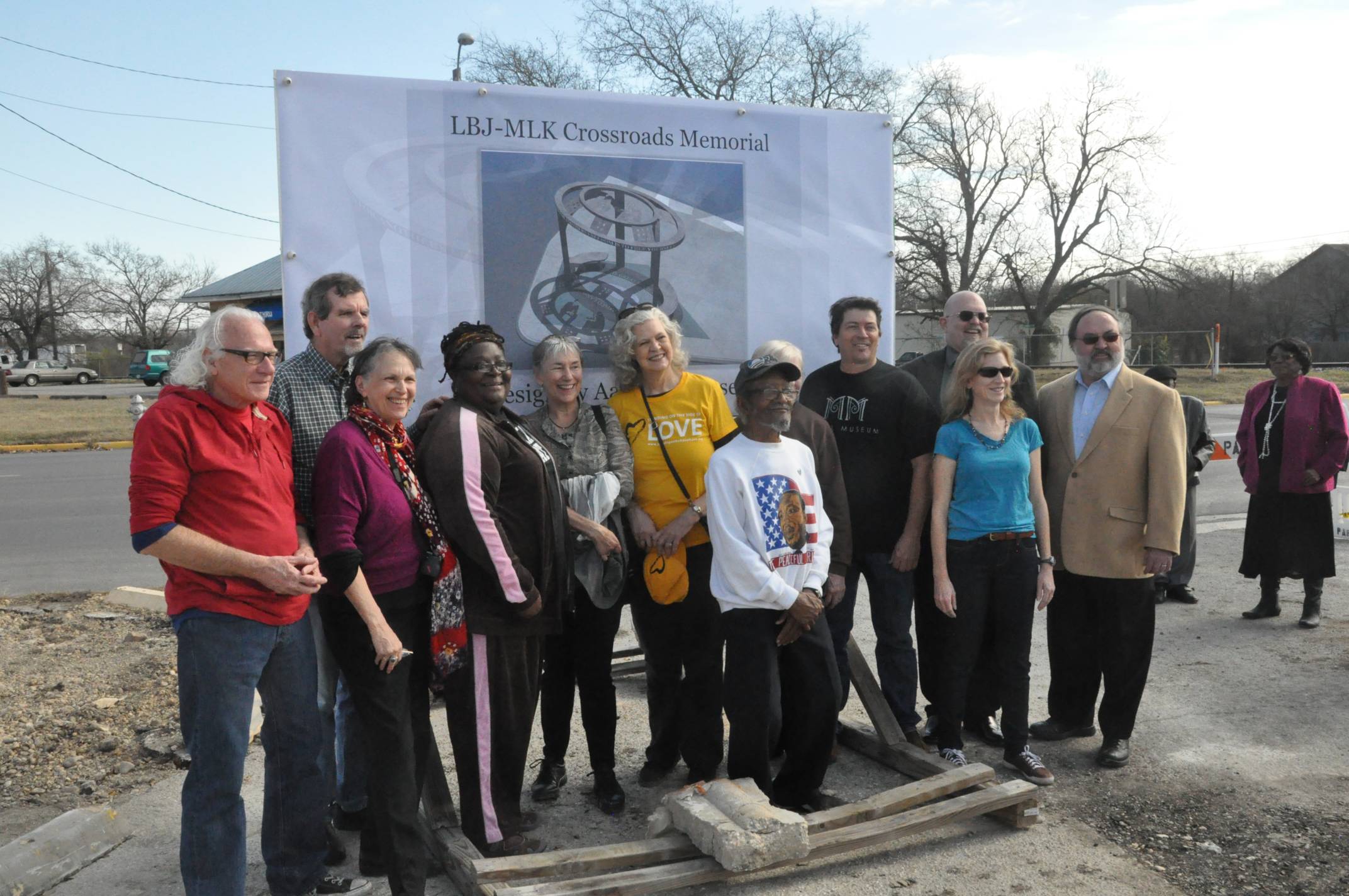 large group of people stand in front of sign that reads LBJ-MLK Crossroads Memorial 