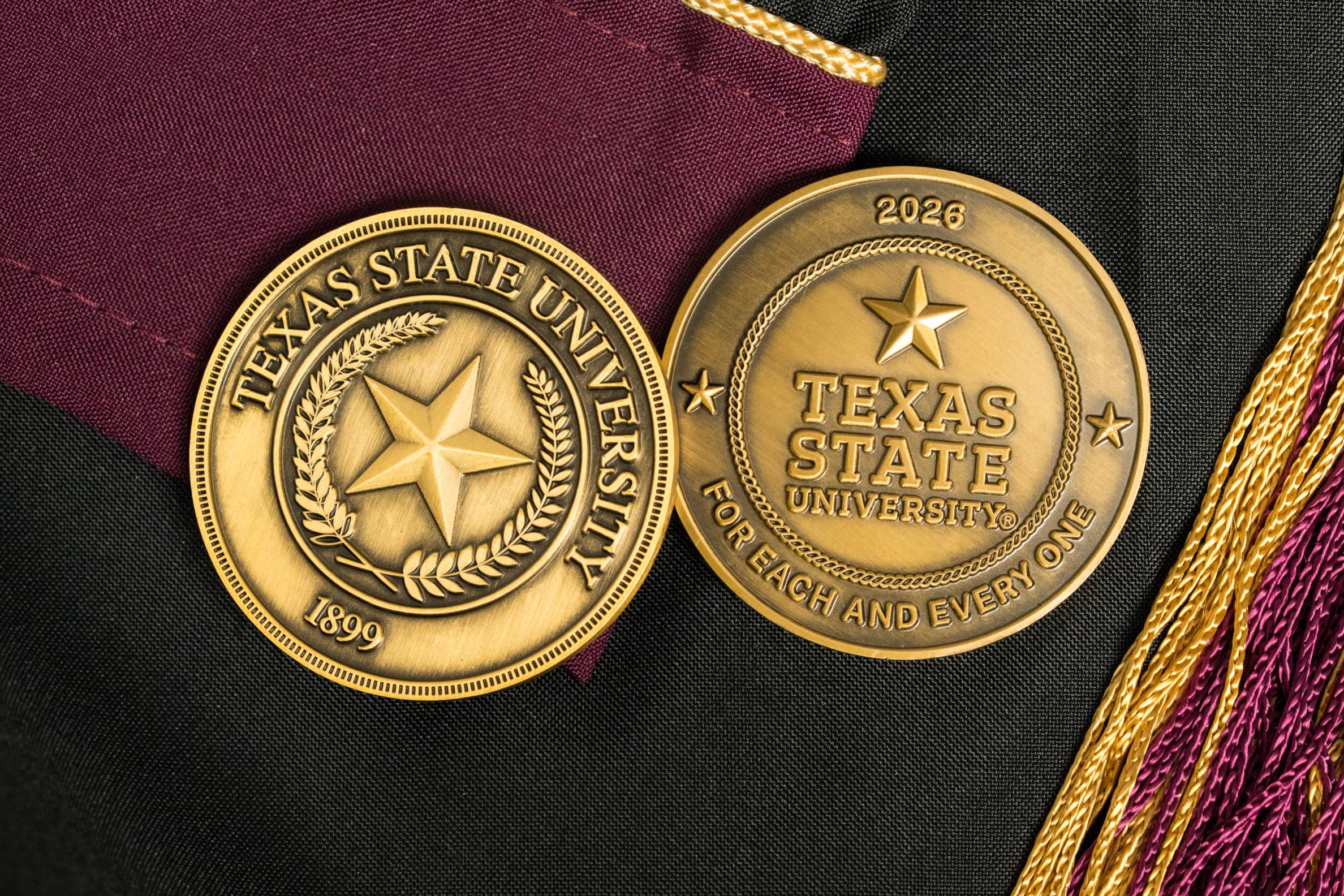 two challenge coins on maroon and black background