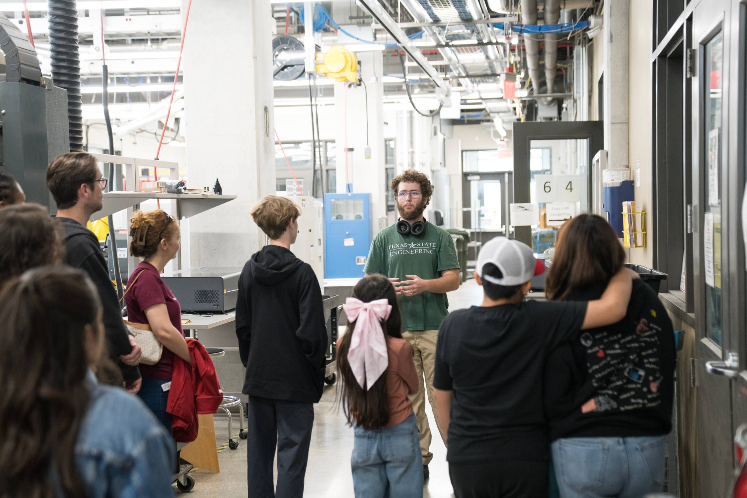 man gives tour of engineering lab to large group of people