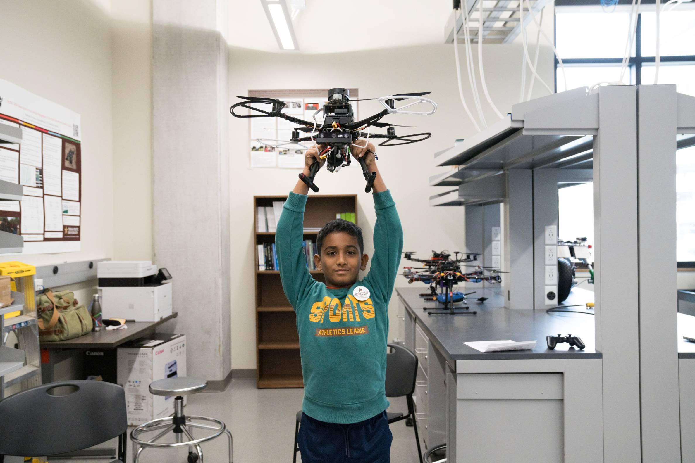 young boy holds up a large drone over his head