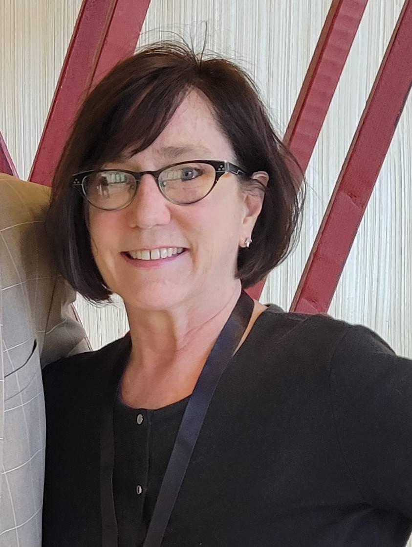 woman with glasses, black blouse, shoulder bag strap visible