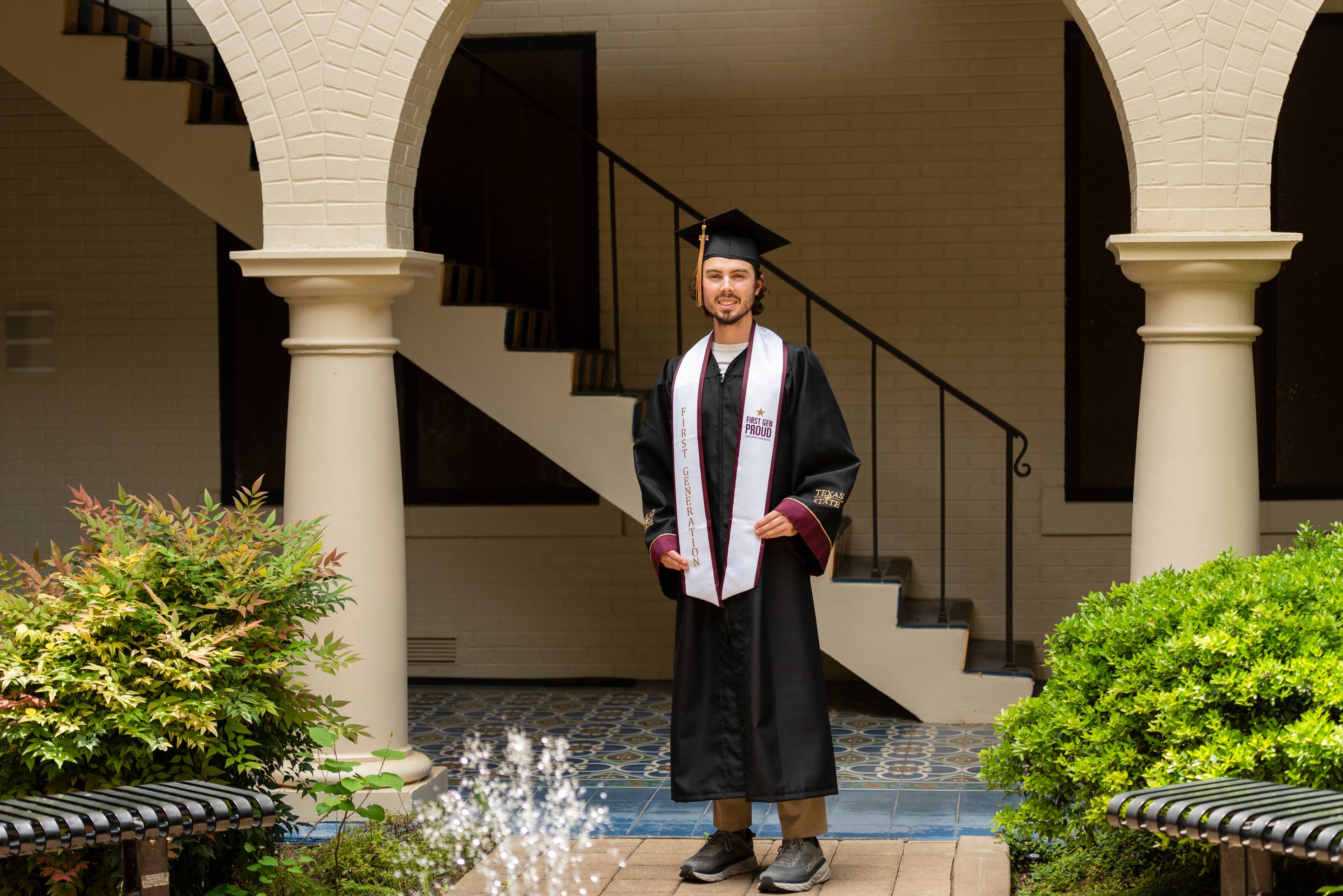 Graduate stands at the base of the staircase in Taylor-Murphy Courtyard.