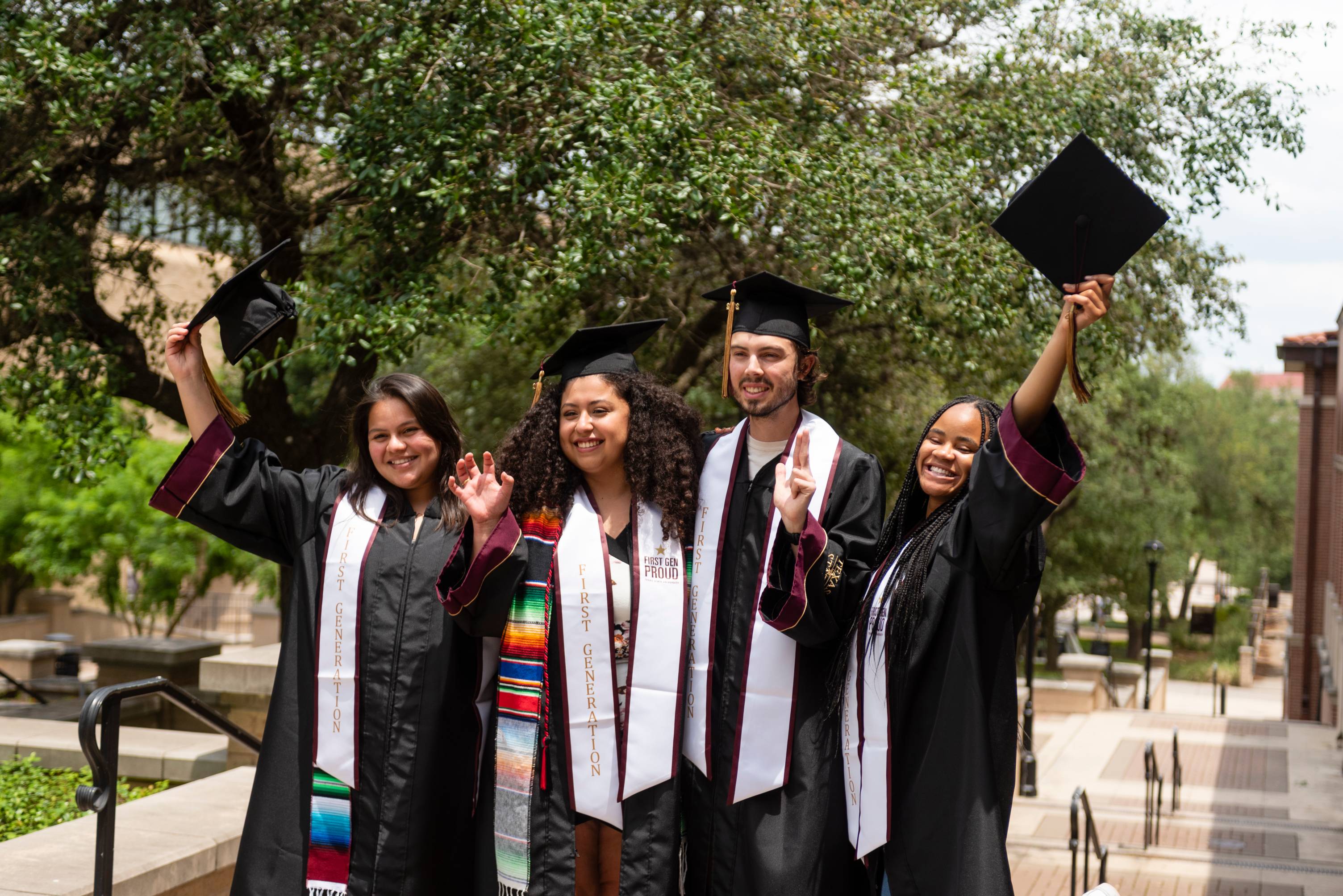 four people in graduation regalia pose for photos
