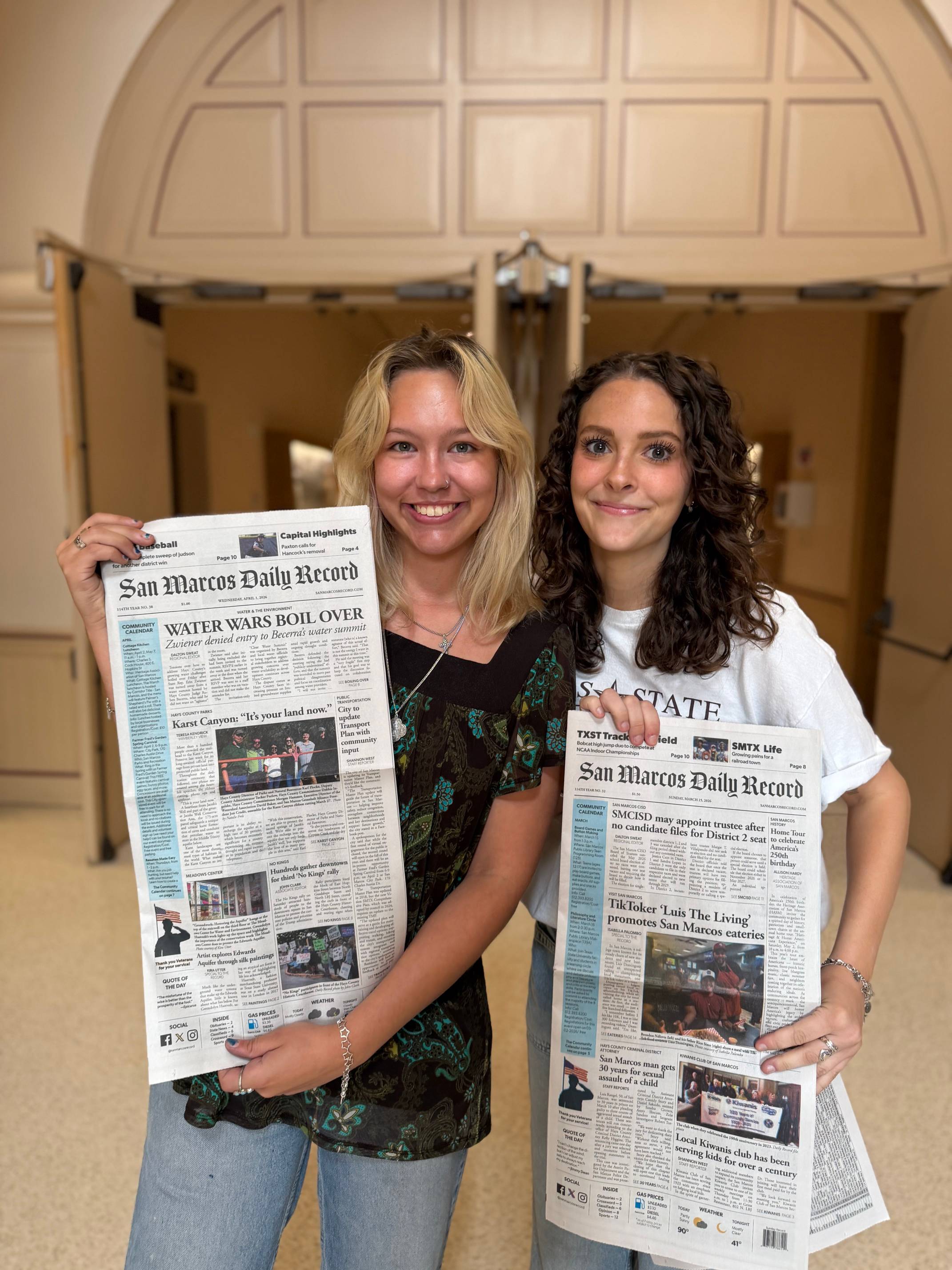 Kira Utter and Isabella Palombo hold their newspapers featuring their articles.