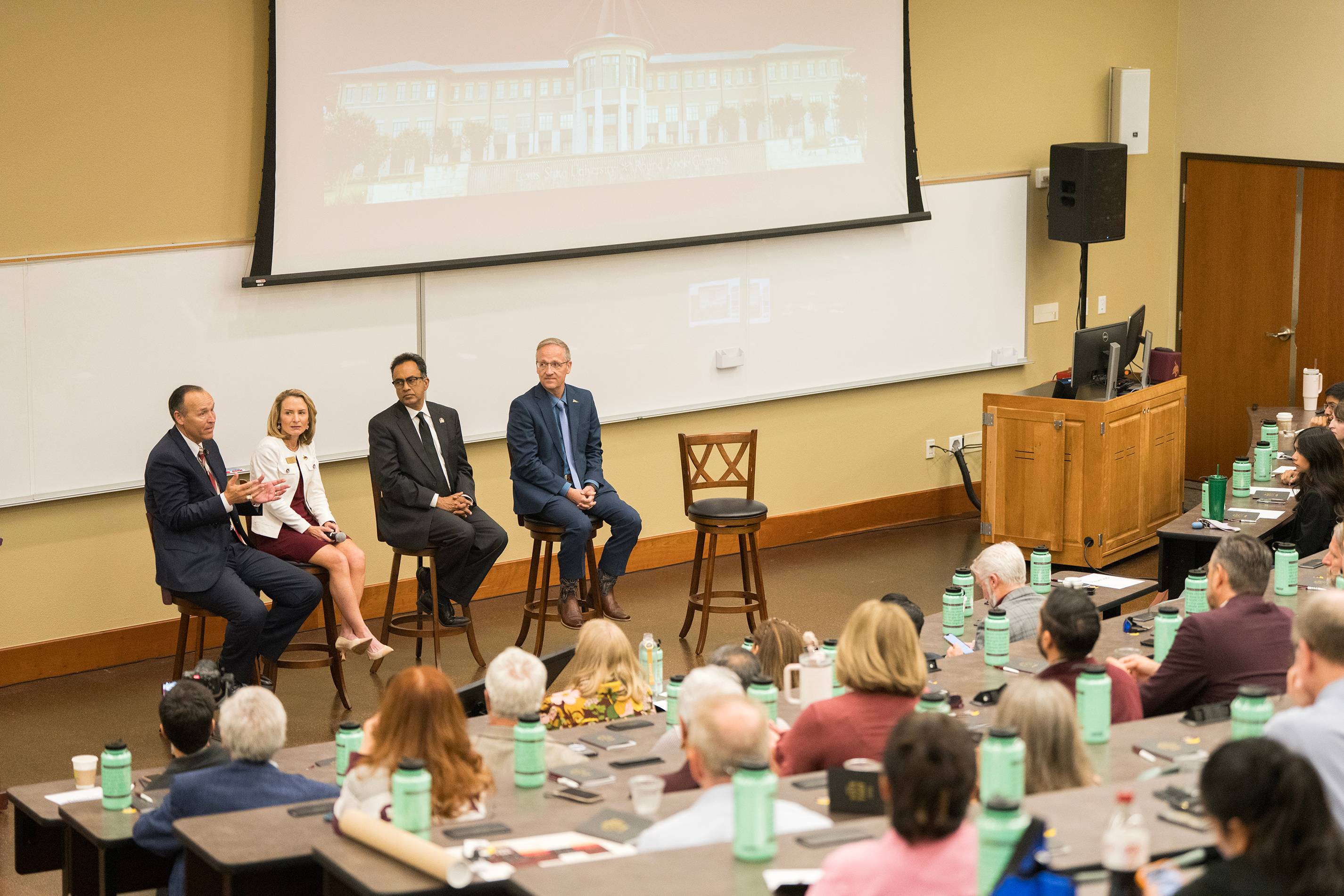 four people participating in panel discussion in front of large audience