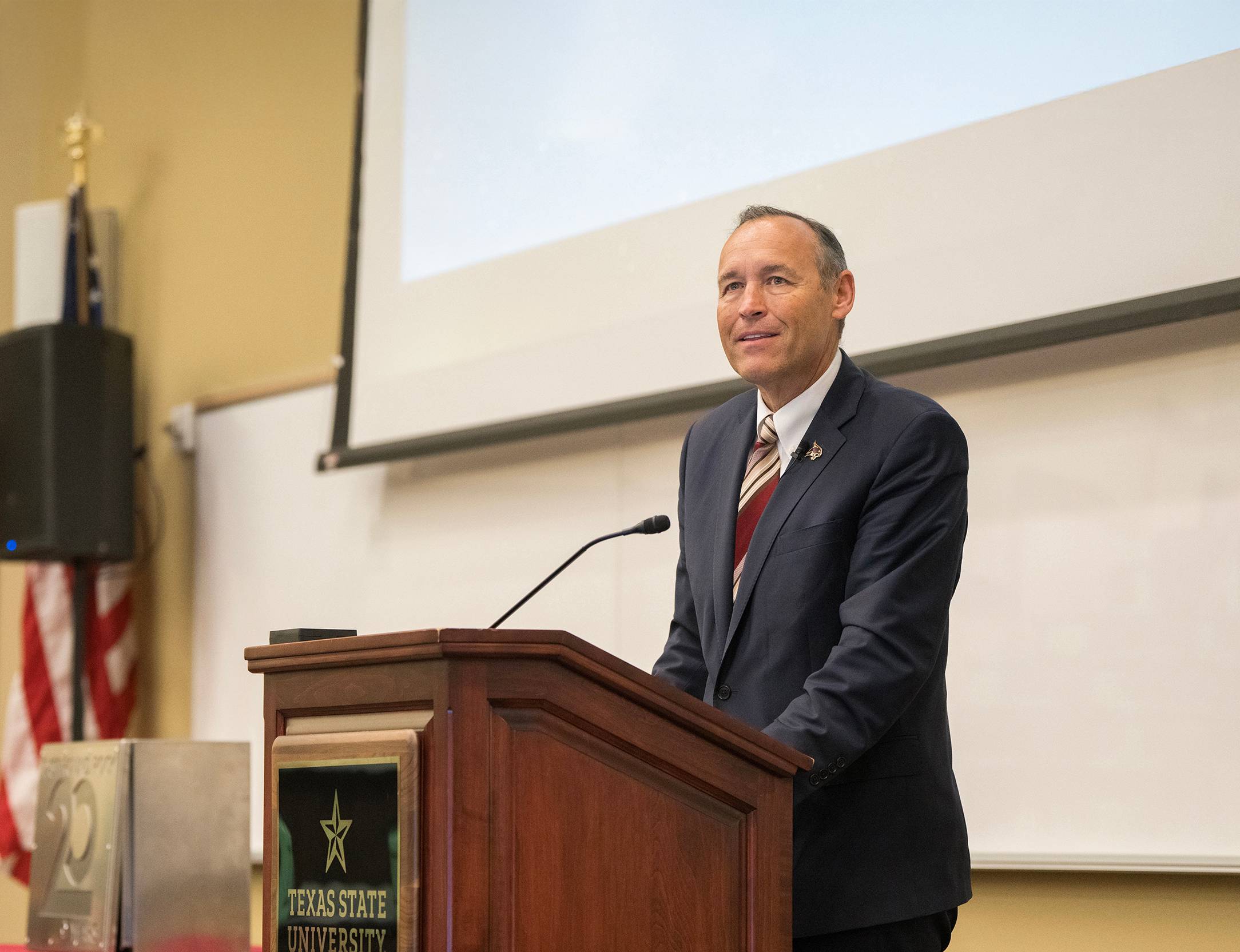 president damphousse speaking at a wooden podium
