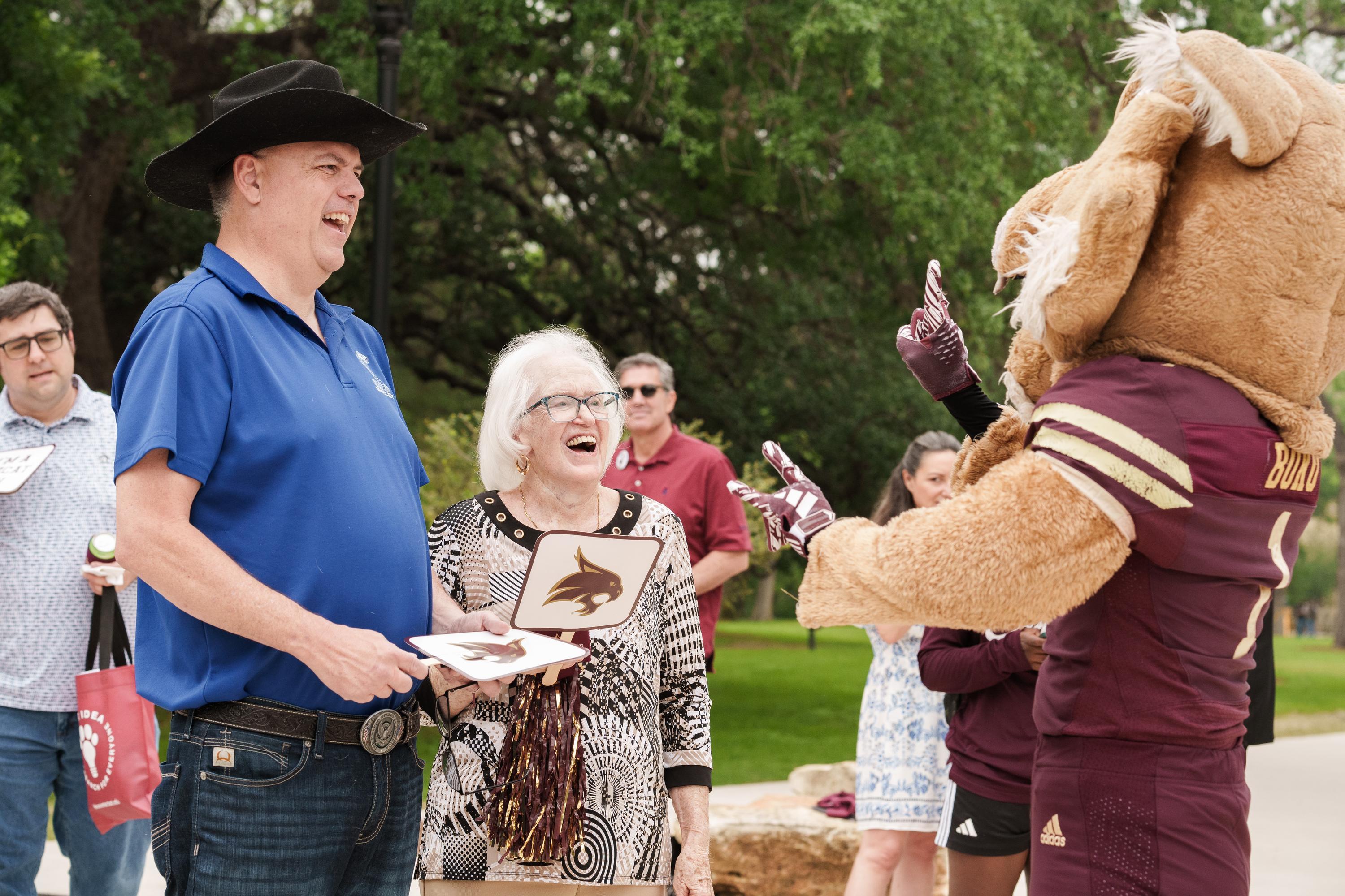 bobcat mascot makes a man and woman laugh