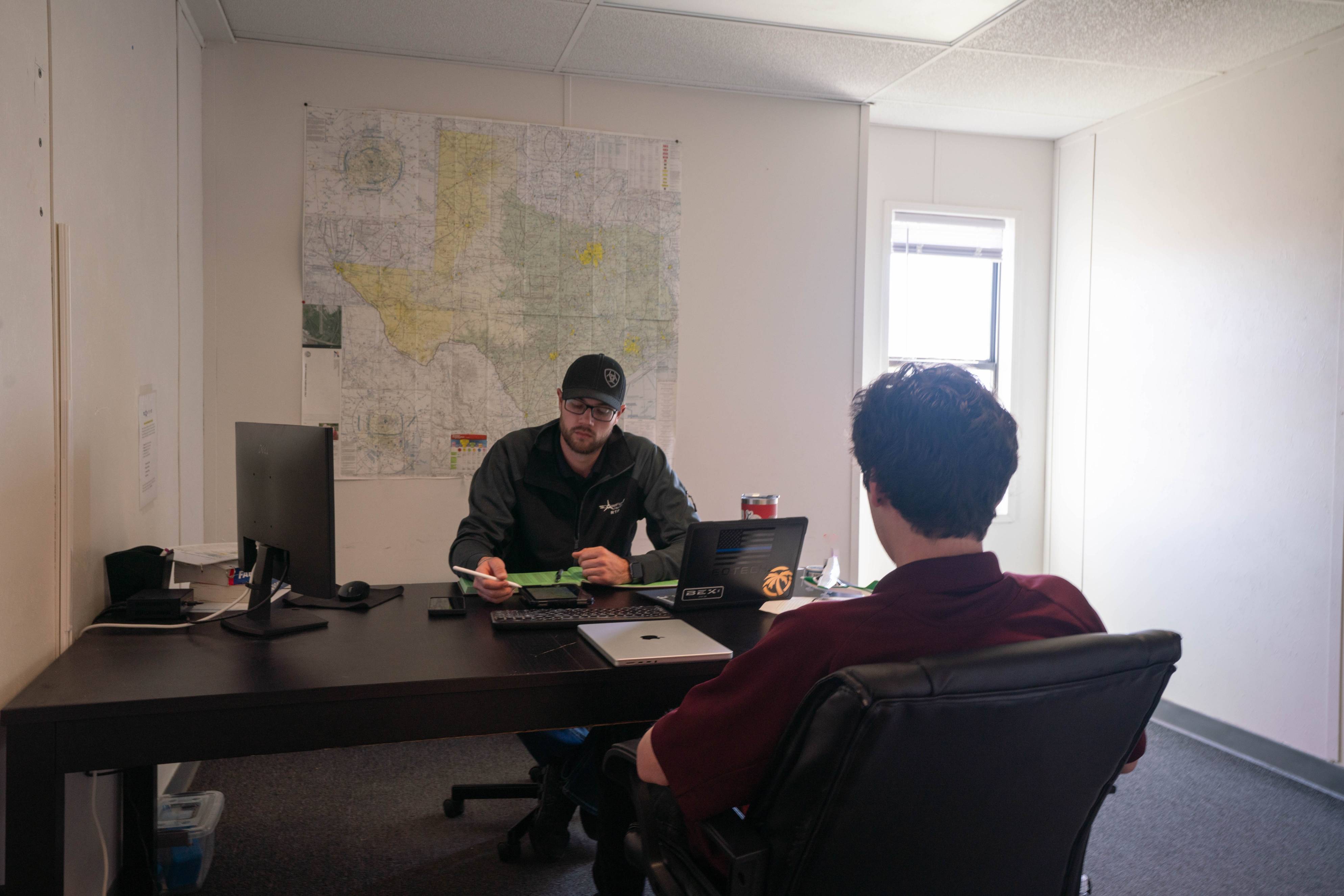 An aviation student sits with a flight instructor in a classroom