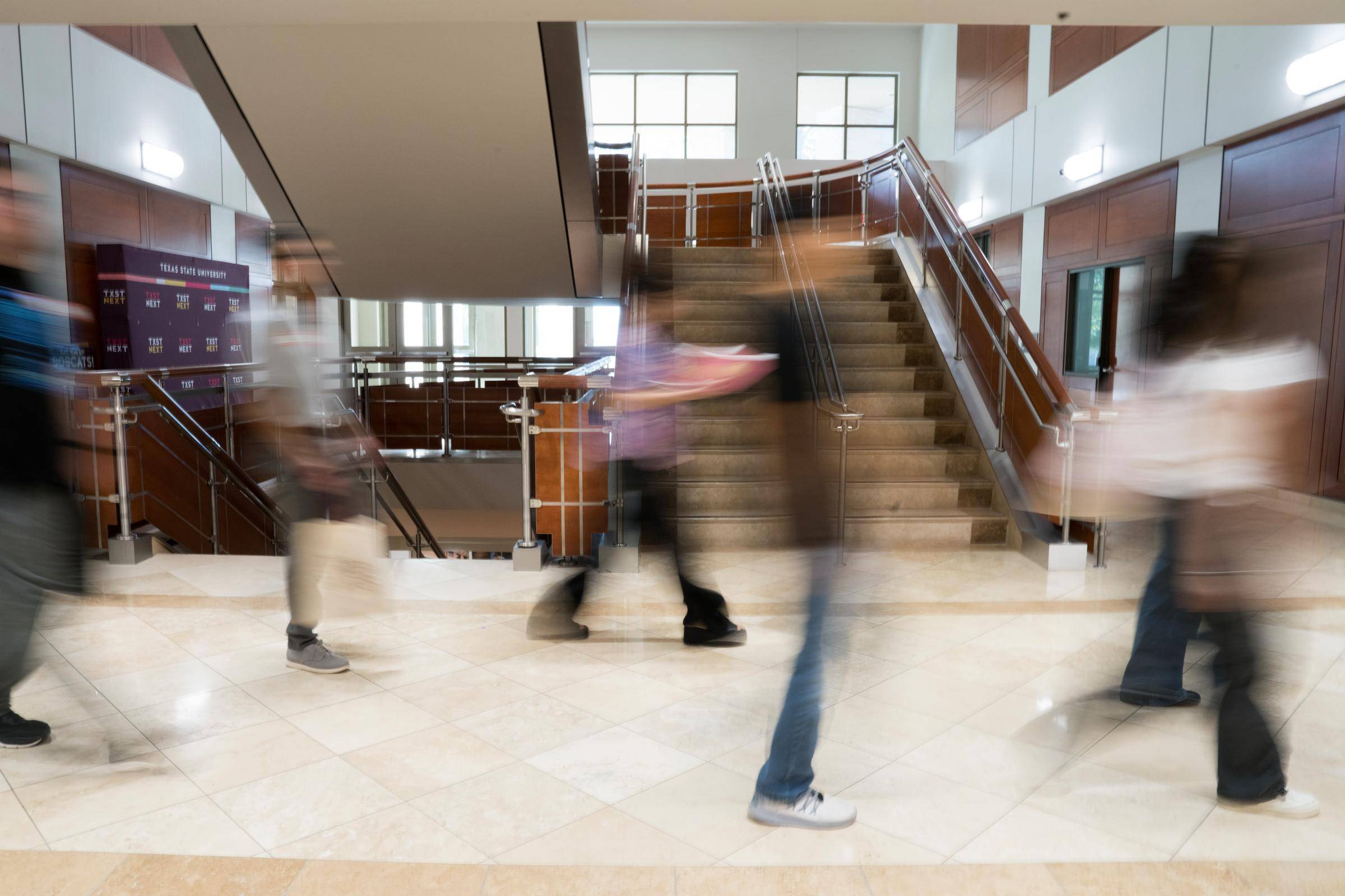 People walking through a hallway at speed.