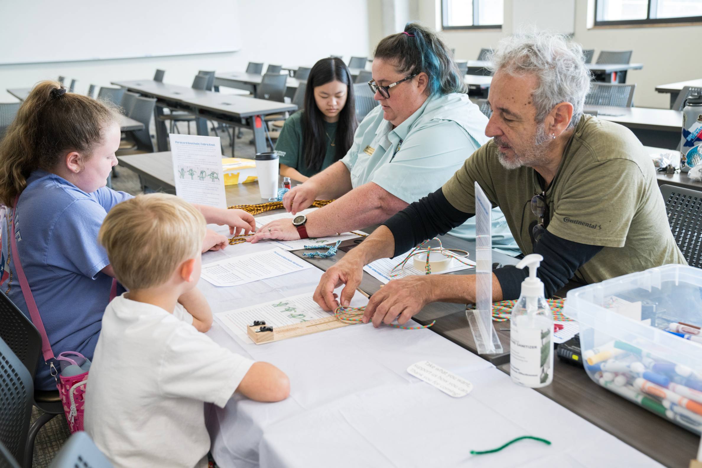 man and woman help young children across a table from them with activities
