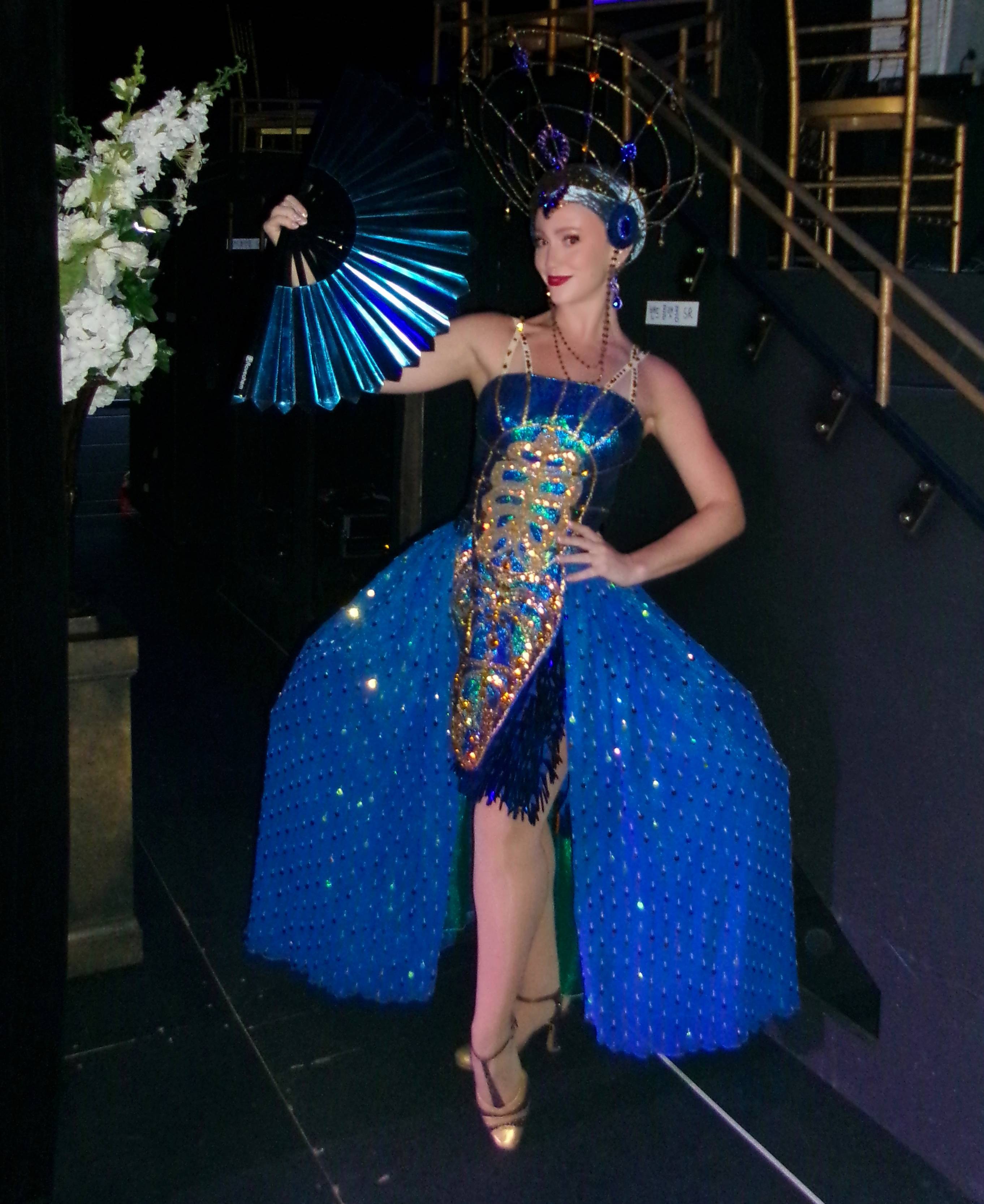 woman in blue custom holds up blue colored hand fan
