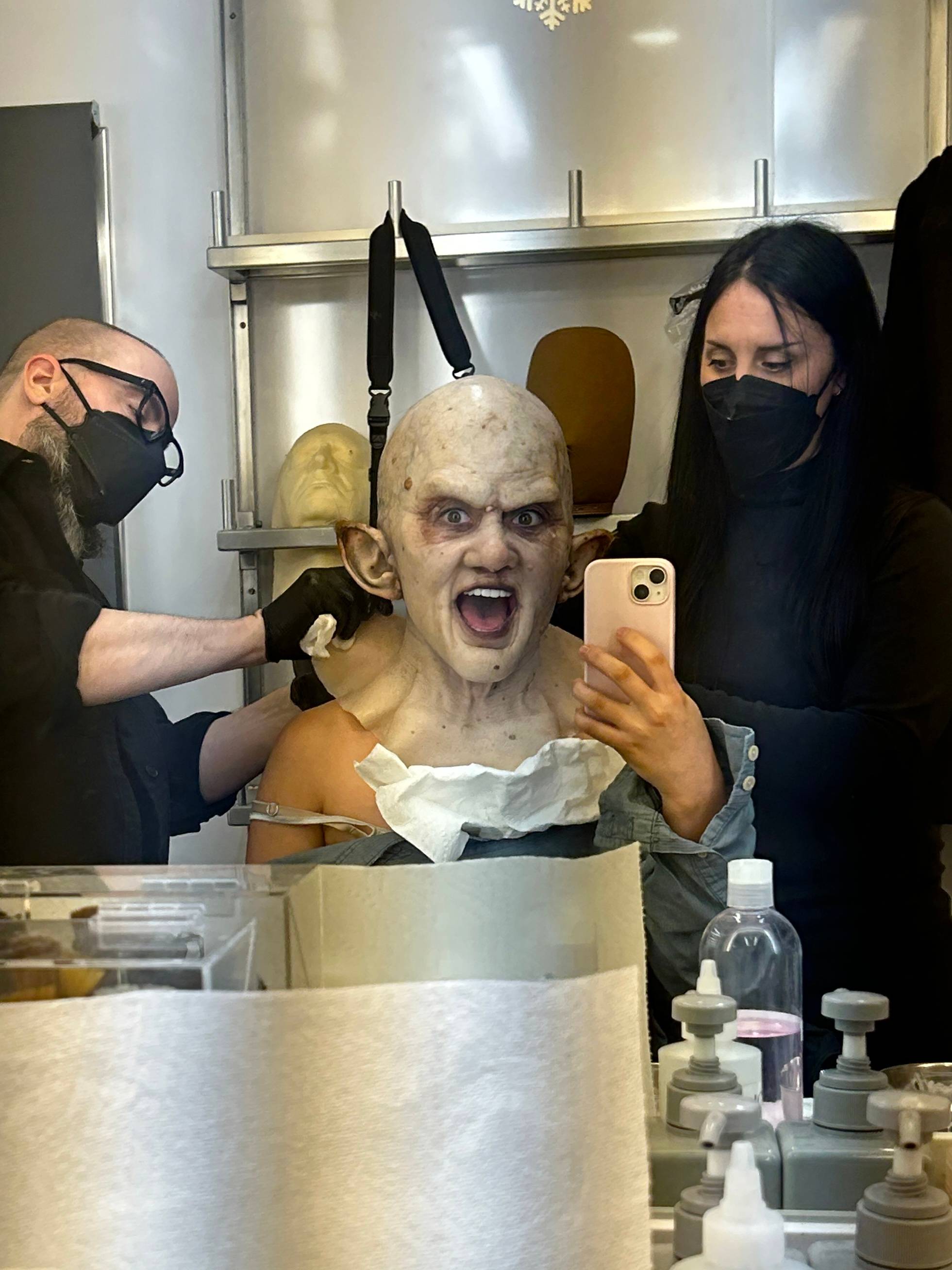 woman takes a selfie while getting special effects make up put on. 