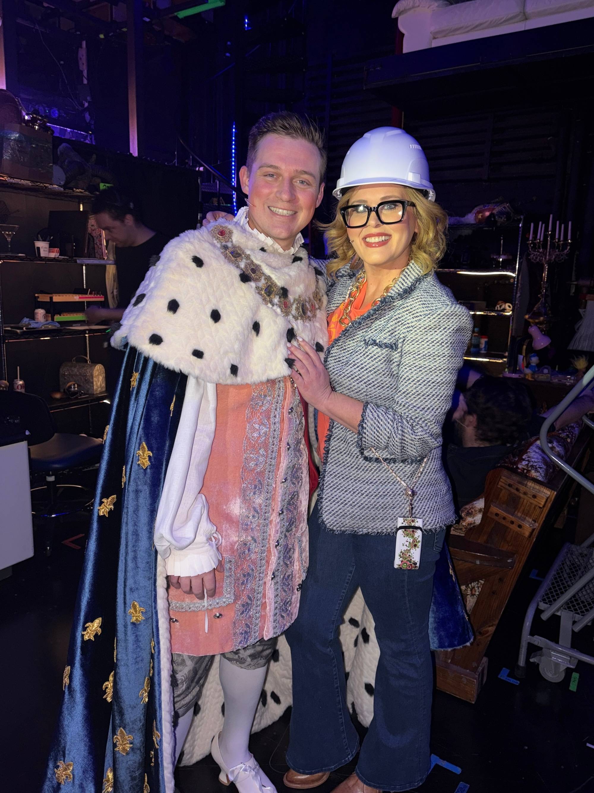 man dress in a king costume poses for a photo with a woman in a hard hat.