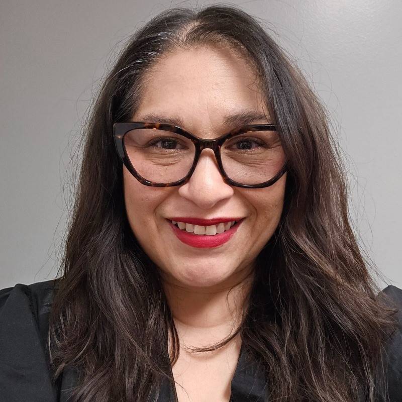 woman with dark hair and glasses smiling at camera