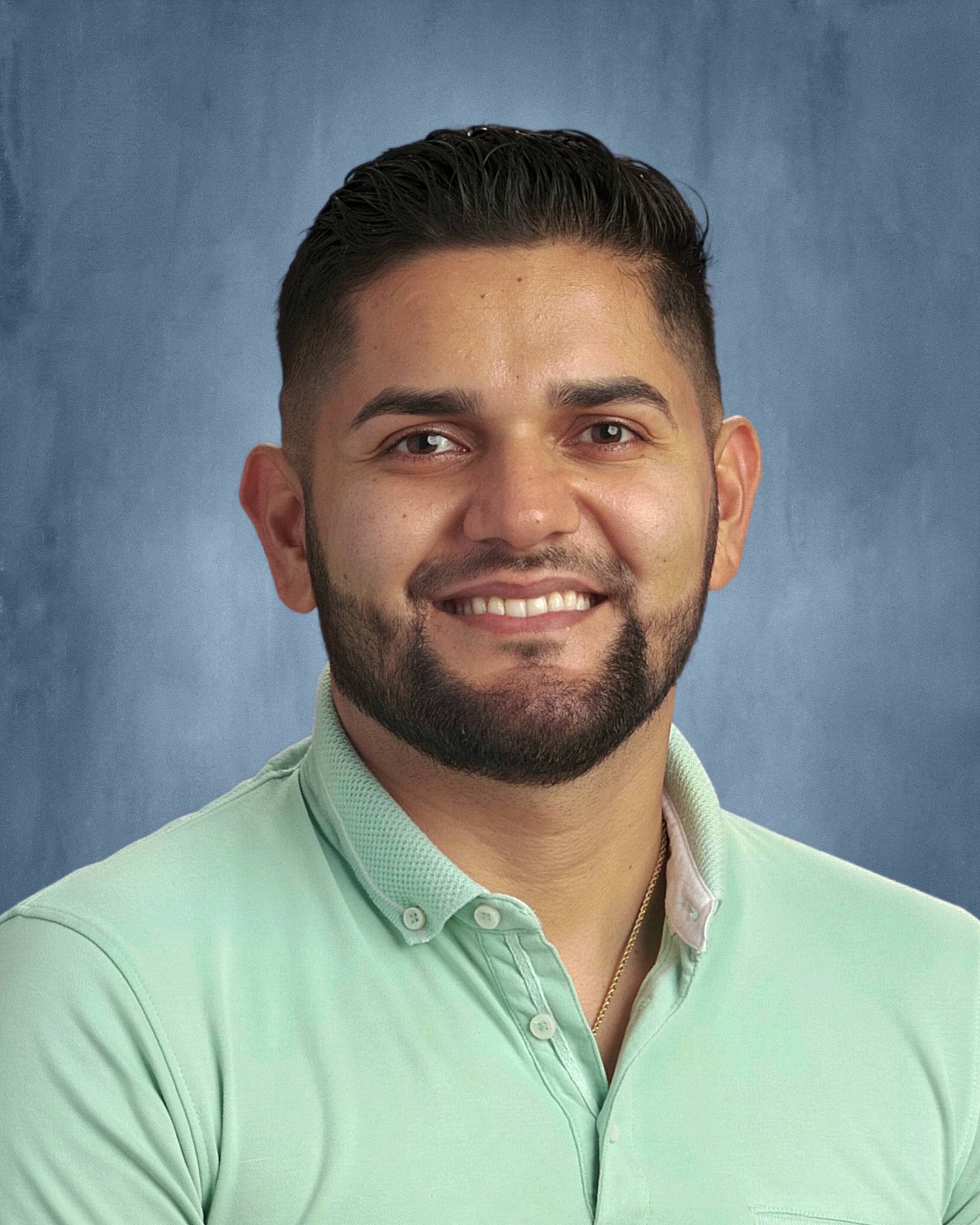 Hispanic man in light green shirt with goatee smiling at camera