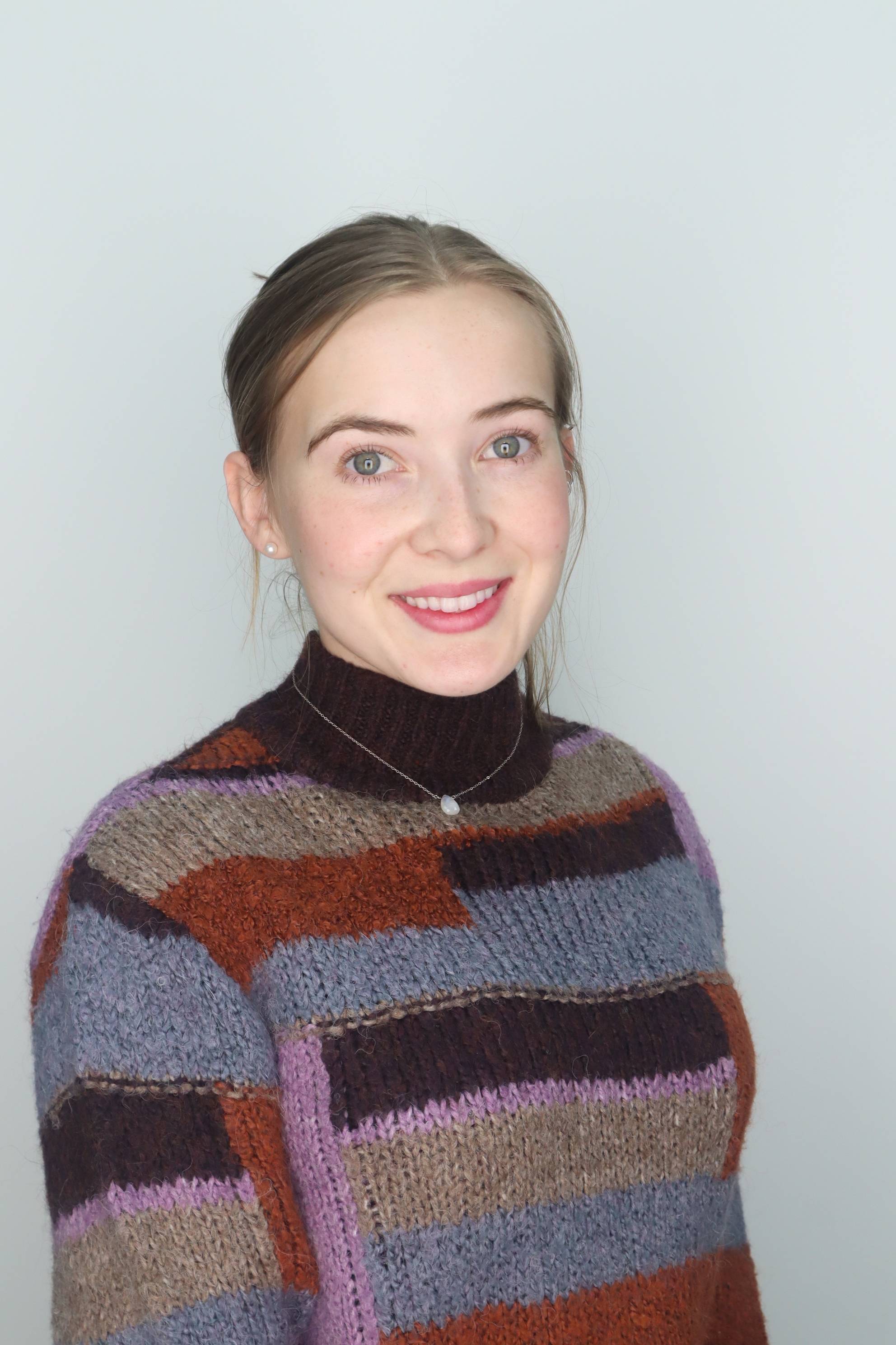 woman in sweater with her hair pulled back smiling at camera